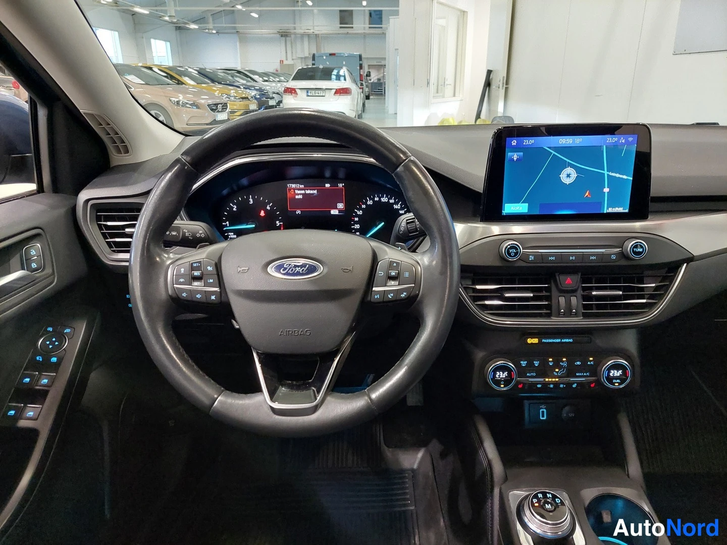 Muu: Ohjaamo kuljettajan puolelta: Ford-ohjauspyörä, mittaristo jossa lukema 172901 km, navigointinäyttö päällä ja ilmastointipaneeli.