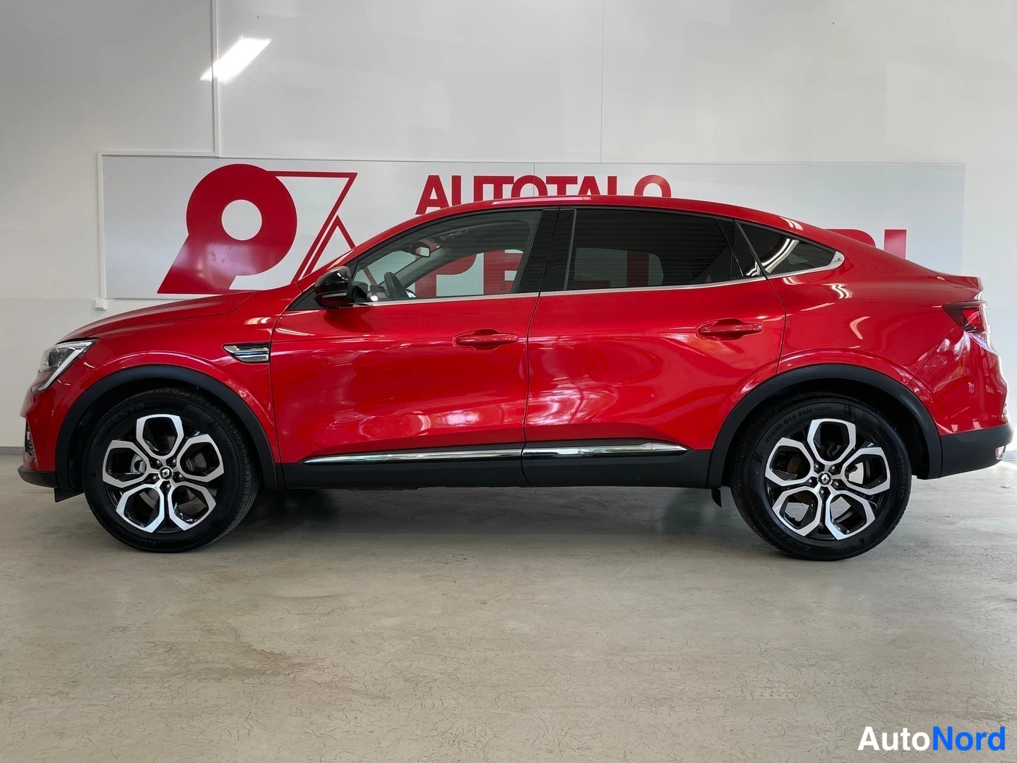Etuviisto, nokka vasemmalle: Punaisen Renault Arkanan etukulmatarkastelu sisätiloissa; keula osoittaa vasemmalle.