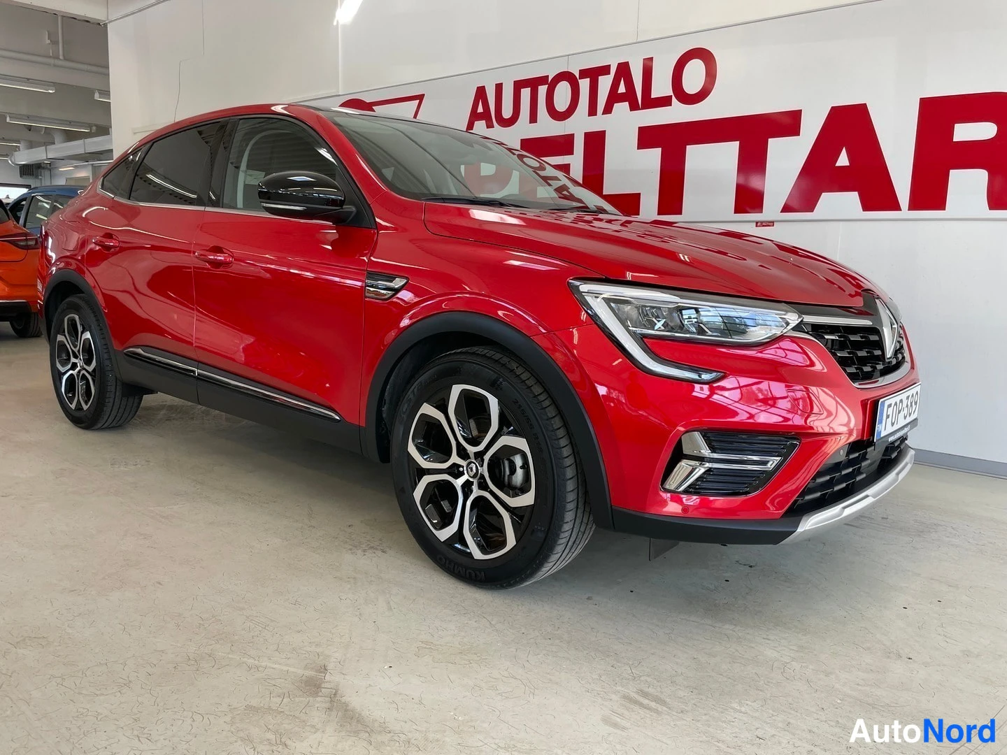 Etuviisto, nokka oikealle: Punaisen Renault Arkanan etukulma oikealta, keulagramiikka ja mustat hottivanteet näkyvissä.