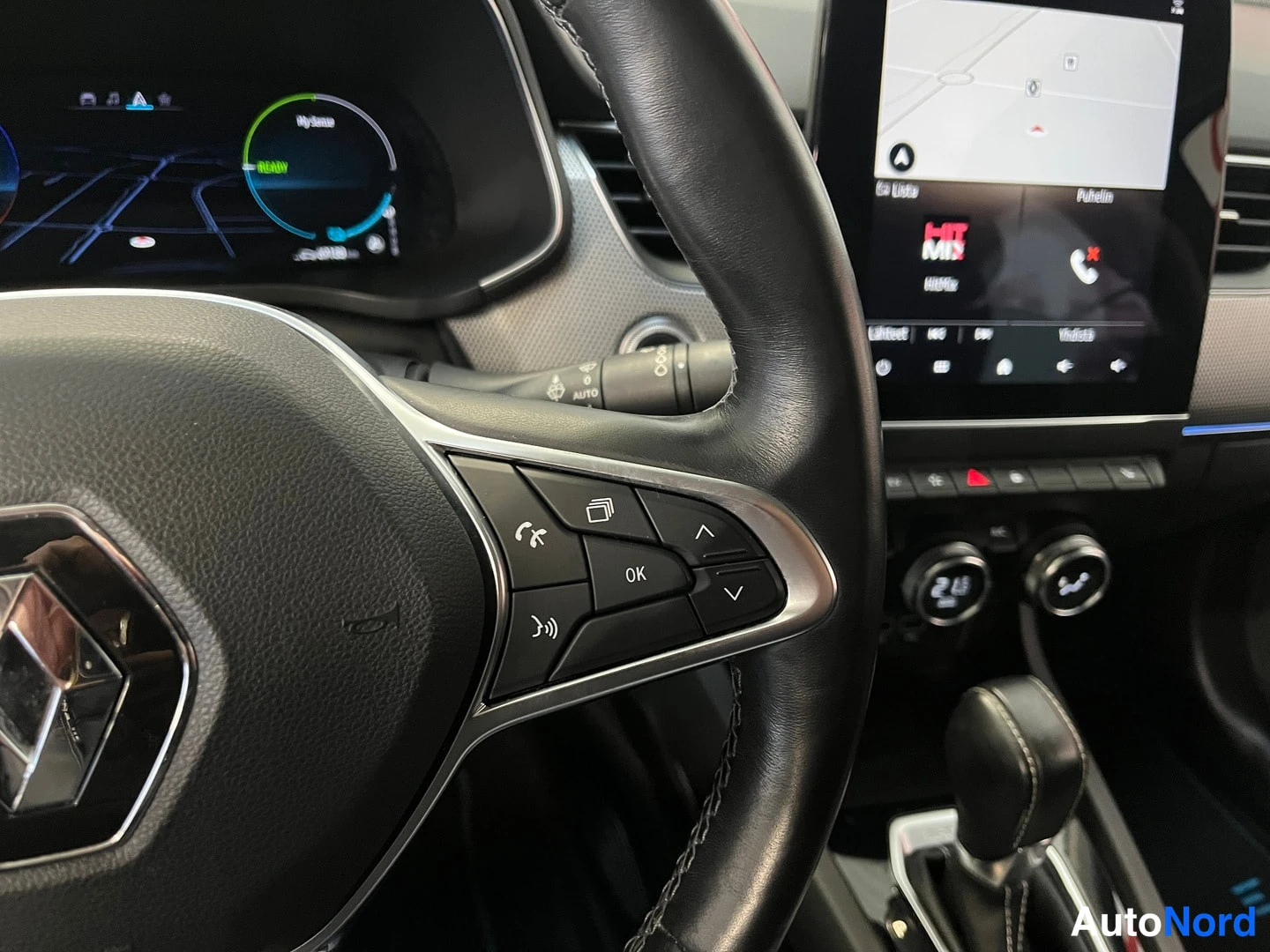 Muu: Renault-ohjauspyörän oikea puolisko ja infotainment-näyttö, jossa kartta, HIT MIX -radiotieto ja puhelinvalikko; autossa automaattivaihteisto.