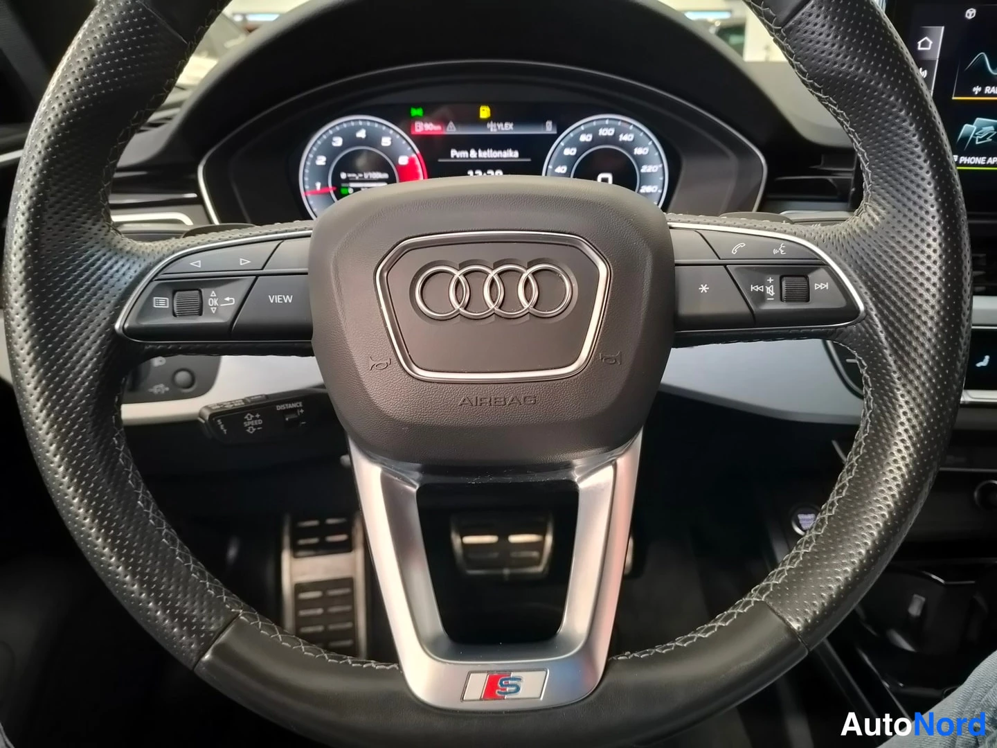 Muu: Audi-ohjauspyörä ja digitaalinen mittaristo lähikuvassa, näytöllä teksti 'Pvm & kellonaika'.