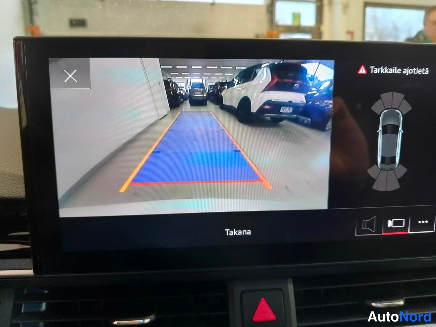 Muu: Hybrid auto display shows rear camera view with parking guidelines, labeled 'Takana', plus a top-view car graphic and warning text 'Tarkkaile ajotietä'.