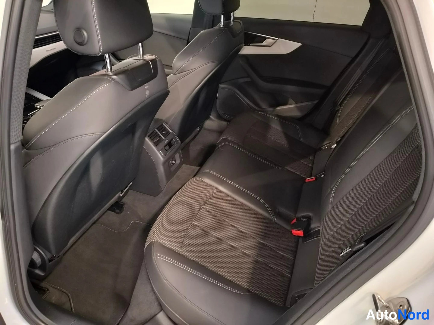 Muu: Rear seats upholstered in black leather/fabric with rear air vents visible through open door.