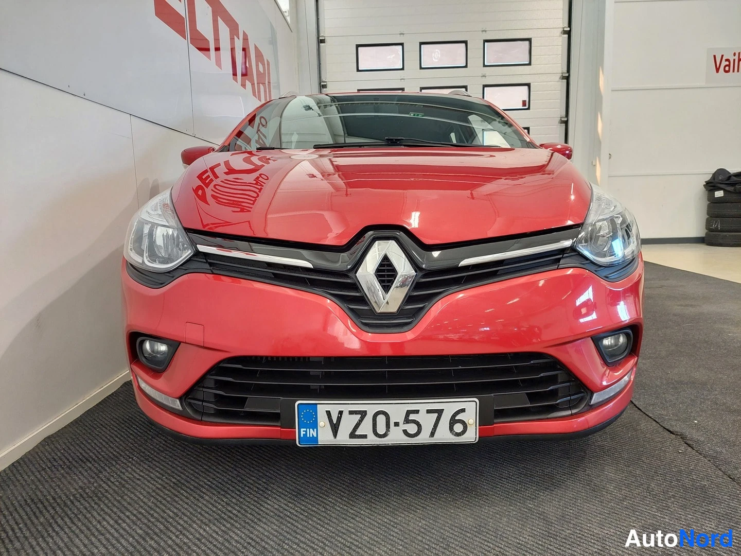 Edestä: Punaisen Renaultin etunäkymä sisätiloissa; rekisterikilpi VZ0-576, keulassa Renault-merkki, sumuvalot ja musta etusäleikkö.