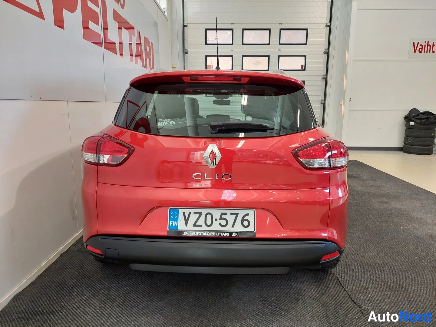 Takaa: Punaisen Renault Clion takanäkymä, rekisterikilpi VZ0-576 ja CLIO-tunnus takaluukussa.