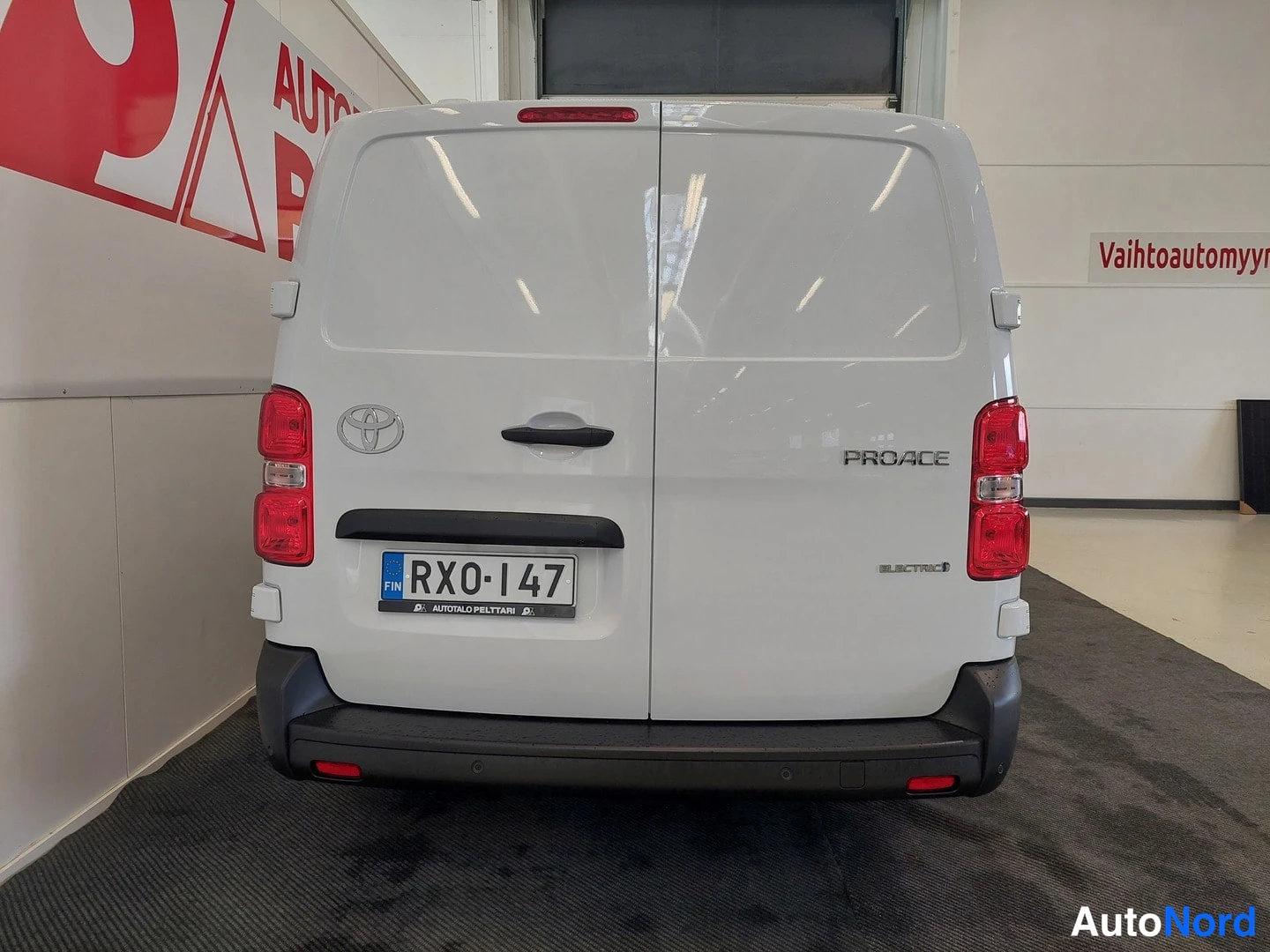 Takaa: Valkoisen pakettiauton takaosa suoraan takaa: Toyota-embleemi, PROACE- ja ELECTRIC-tekstit, punaiset takavalot ja rekisterikilpi.