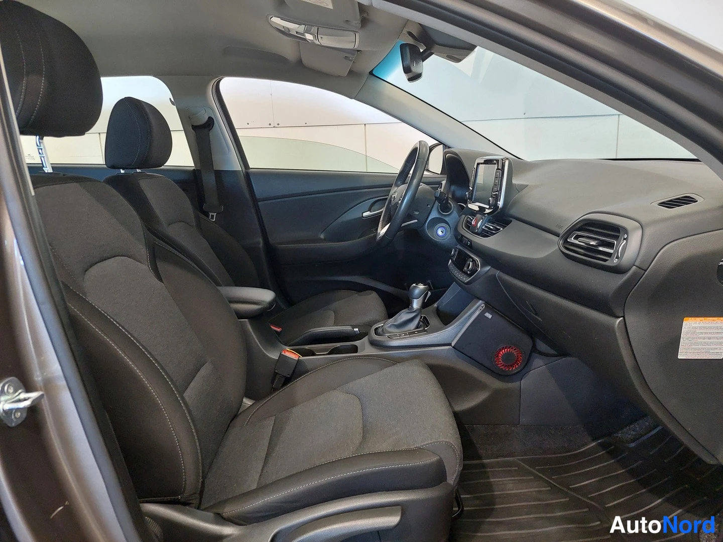 Muu: Hyundai i30:n etumatkustustila: tummat kangasistuimet, rattisivistykset, vaihtajan ja kojetaulu näkyvät.