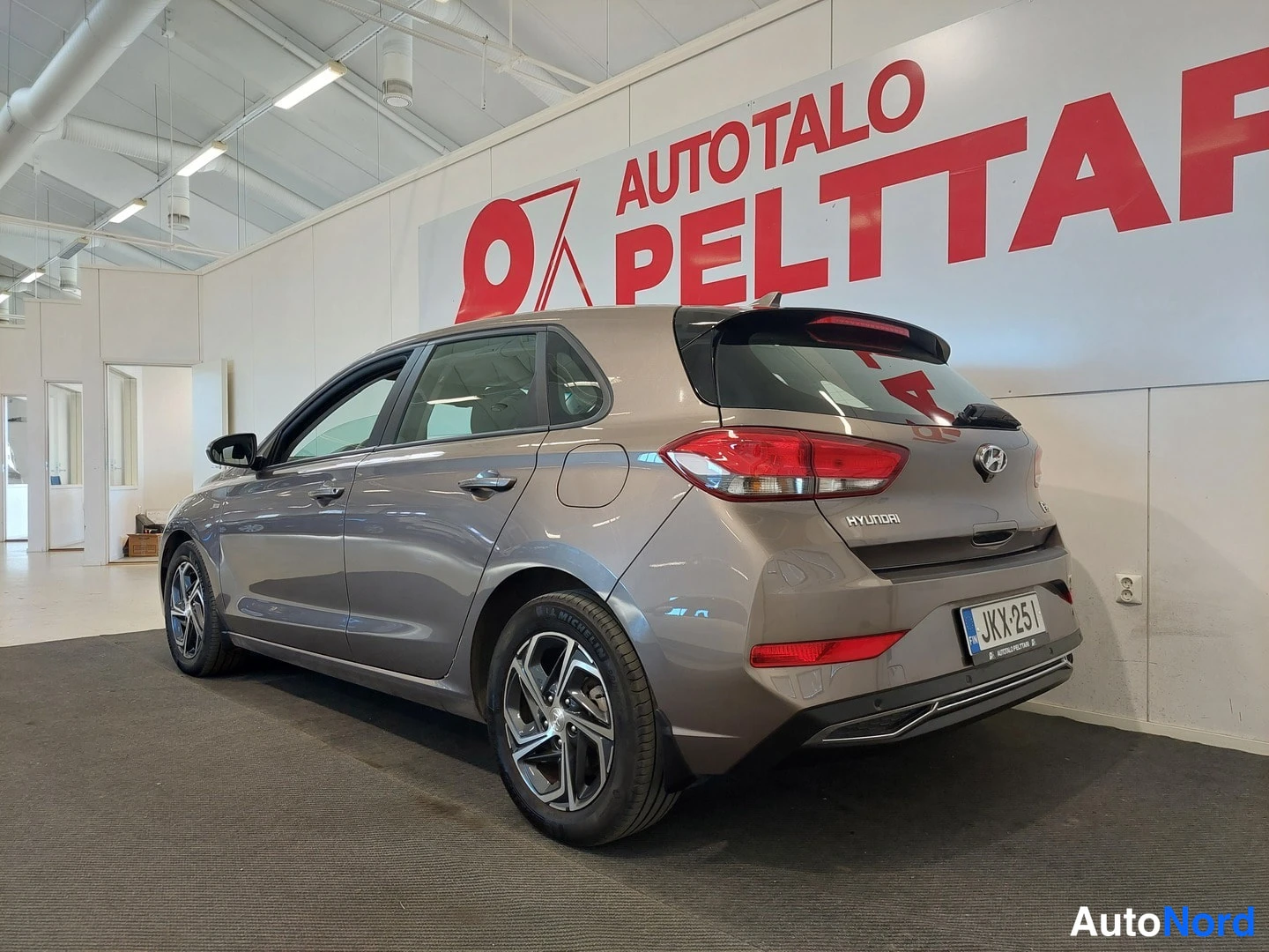 Takaviisto: Hyundai i30:n takakulma auton oikealta sivulta kuvattuna sisätilassa; rekisterikilpi ja HYUNDAI-tunnus takaluukussa.