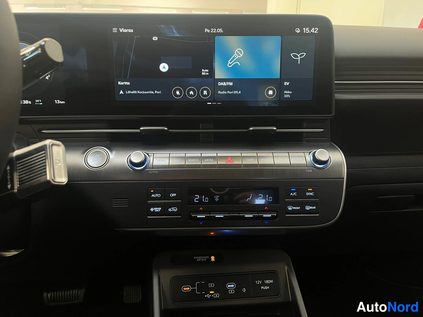 Muu: Hyundai Kona Electricin keskusnäyttö ja ilmastointipaneeli, akun lataustaso 38 % ja lämmöt 21 asteessa.