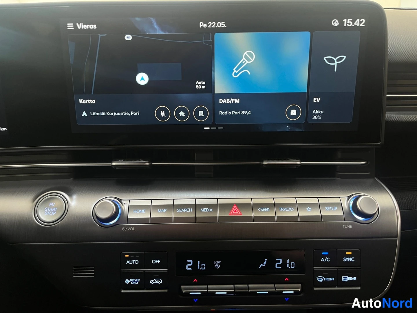 Muu: Kojelaudan infotainment-näyttö näyttää karttaa, DAB/FM-radioa ja EV-akun tilan (38%), alla kosketusnapit ja kaksivyöhykkeinen automaattinen ilmastointi (21/21 a