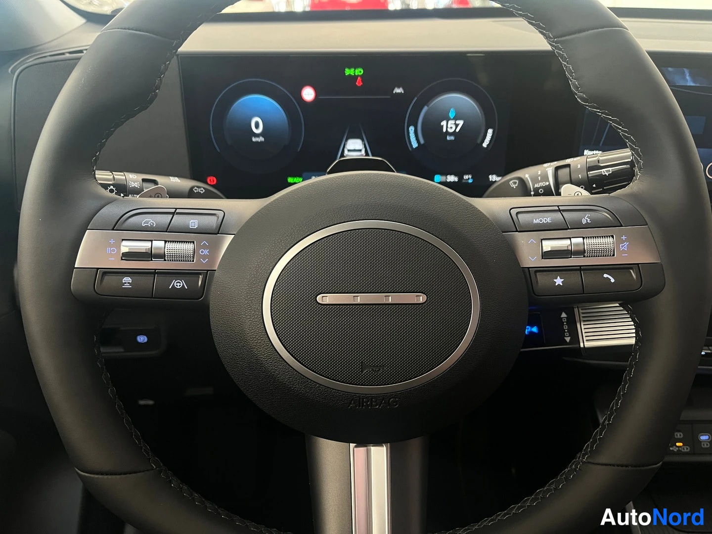 Muu: Hyundai Kona Electricin ratin ja kojelaudan lähikuva, näytössä 157 km toimintamatka.