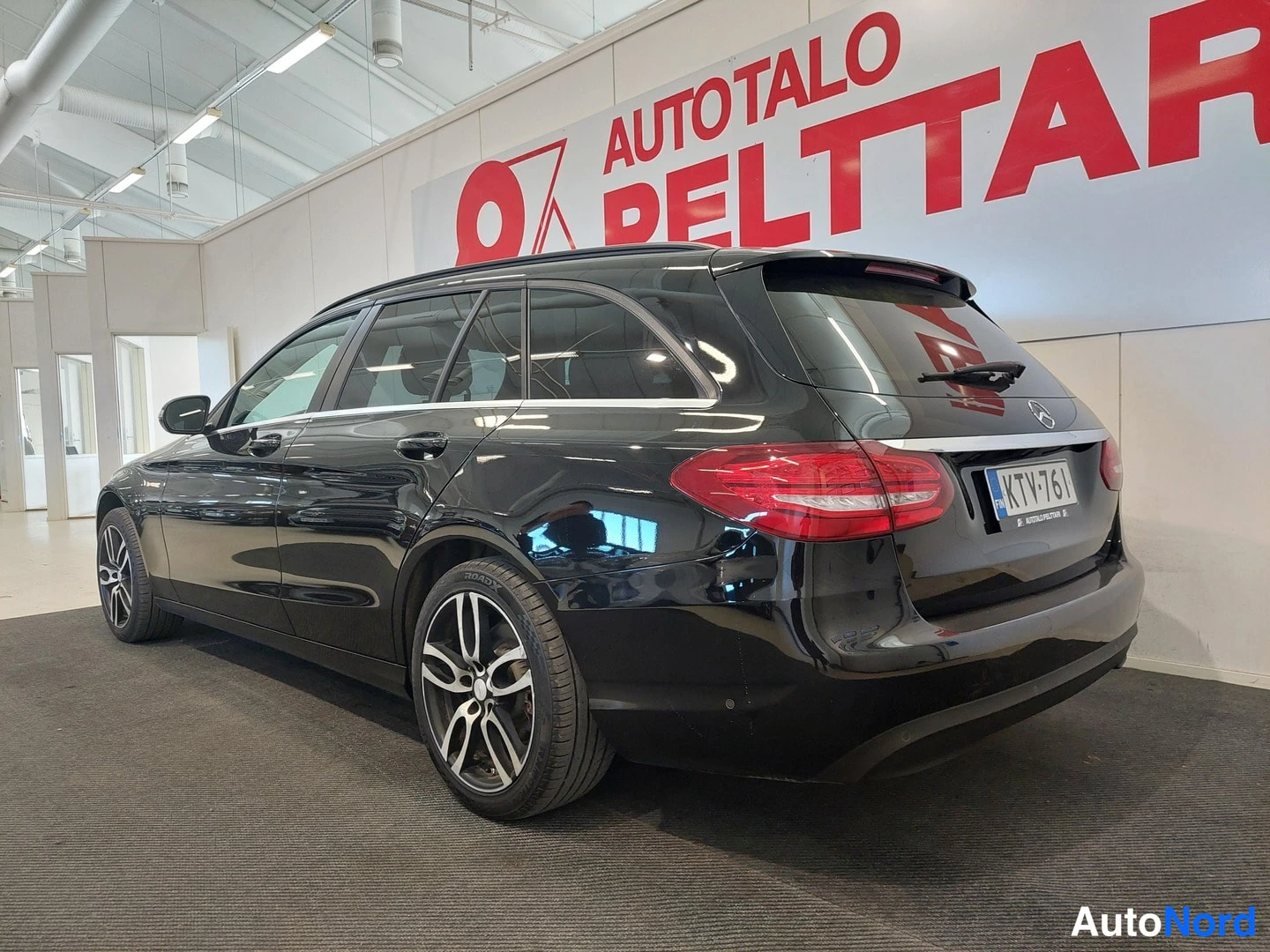 Takaviisto: Mustan farmarikorisen Mercedes-Benzin takakulma sisätiloissa, takapanssi ja kylki näkyvissä, rekisterikilpi.