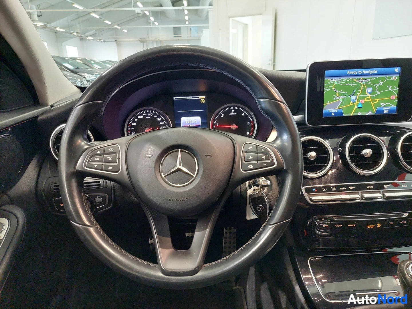 Edestä: Ohjauspyörä lähikuvassa: Mercedes-tähti, AIRBAG-teksti, monitoiminäppäimet ja takana mittariston tietonäyttö.