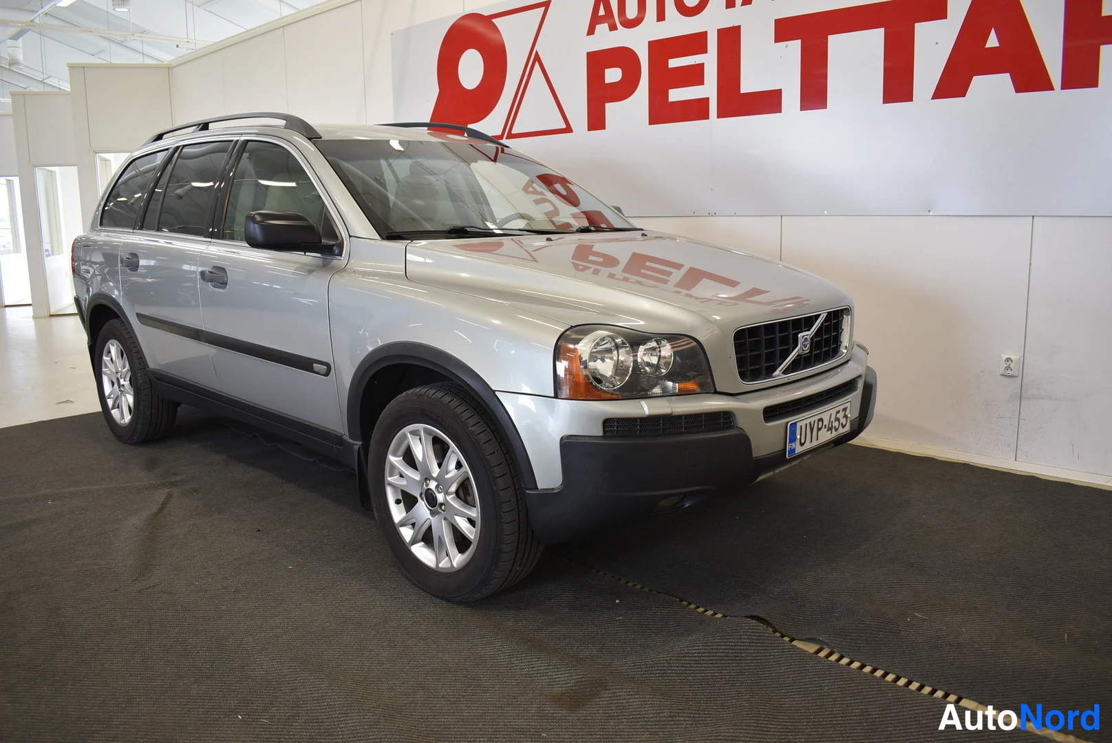 Etuviisto, nokka oikealle: Hopeanharmaa SUV etuosa oikealta kolmivartalokulmassa sisätiloissa, rekisterikilpi.