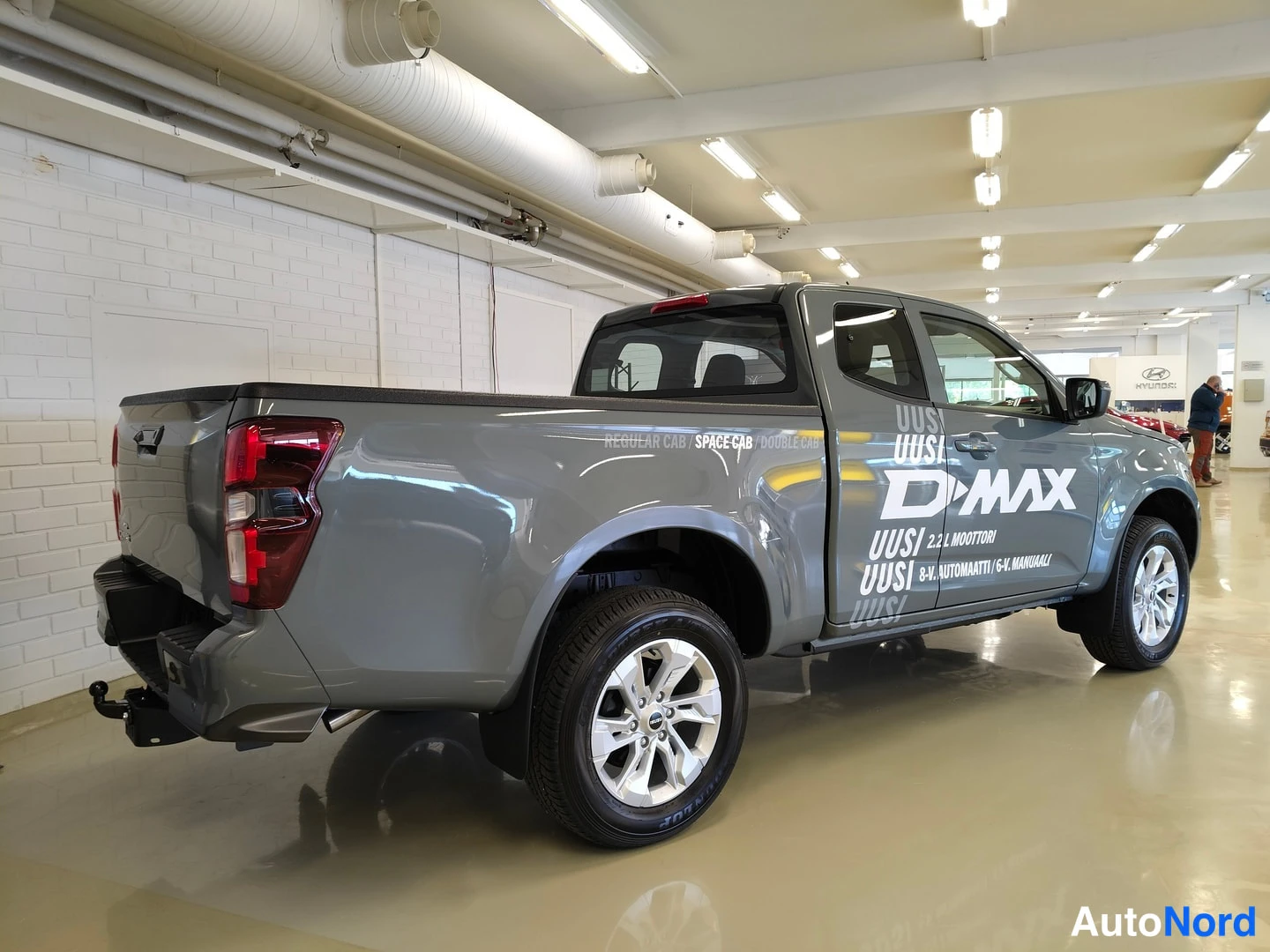 Takaviisto: Harmaan Isuzu D-Max -lavauttava pick-upin takakulma vasemmalta, lavan takapaneeli ja pyörät näkyvät
