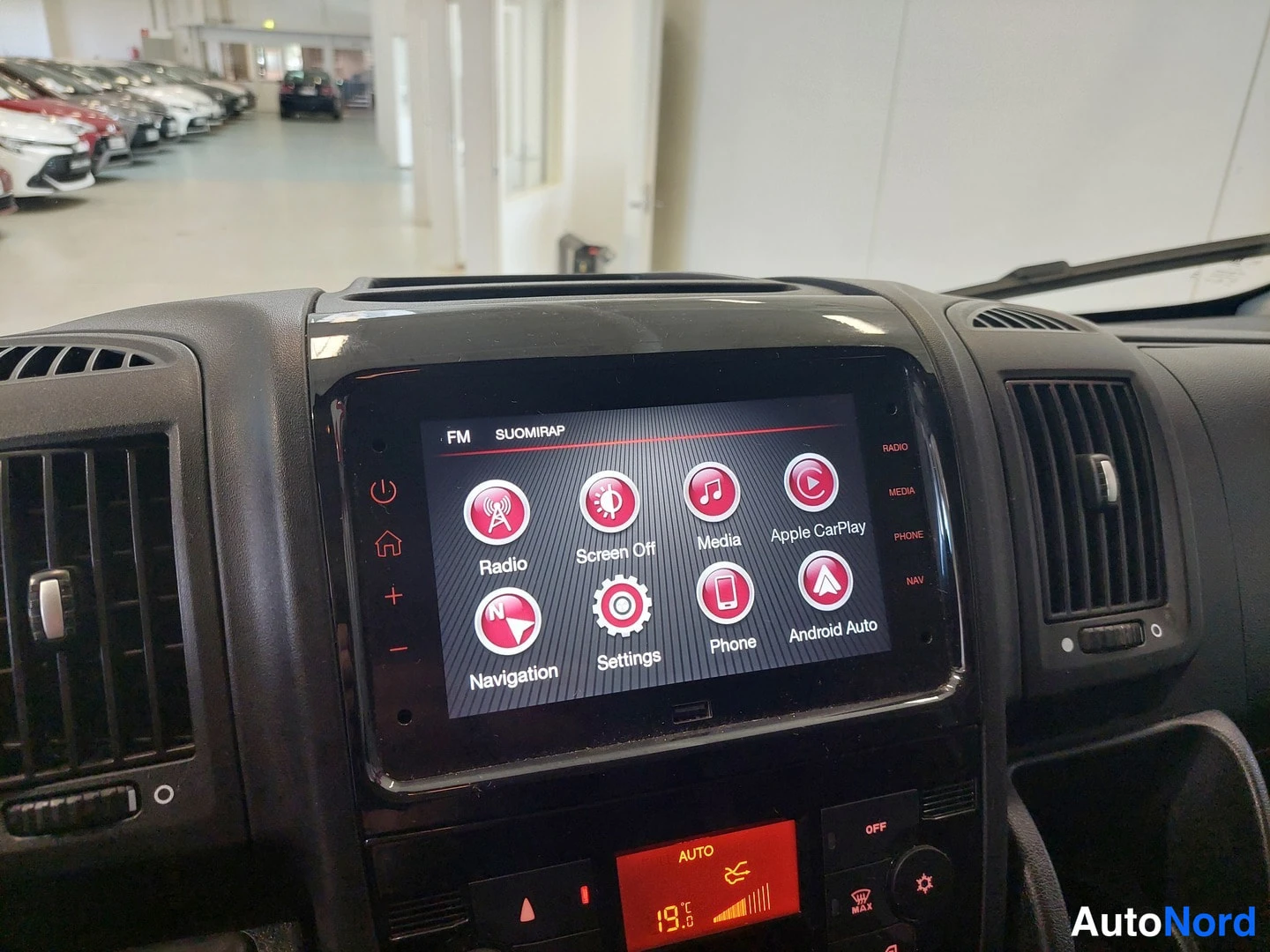 Muu: Keskusnäytön lähikuva: ruudulla Radio-, Media-, Apple CarPlay-, Android Auto-, Navigation- ja Phone-toiminnot, alla automaattisen ilmastoinnin ASETUKSET-paneeli