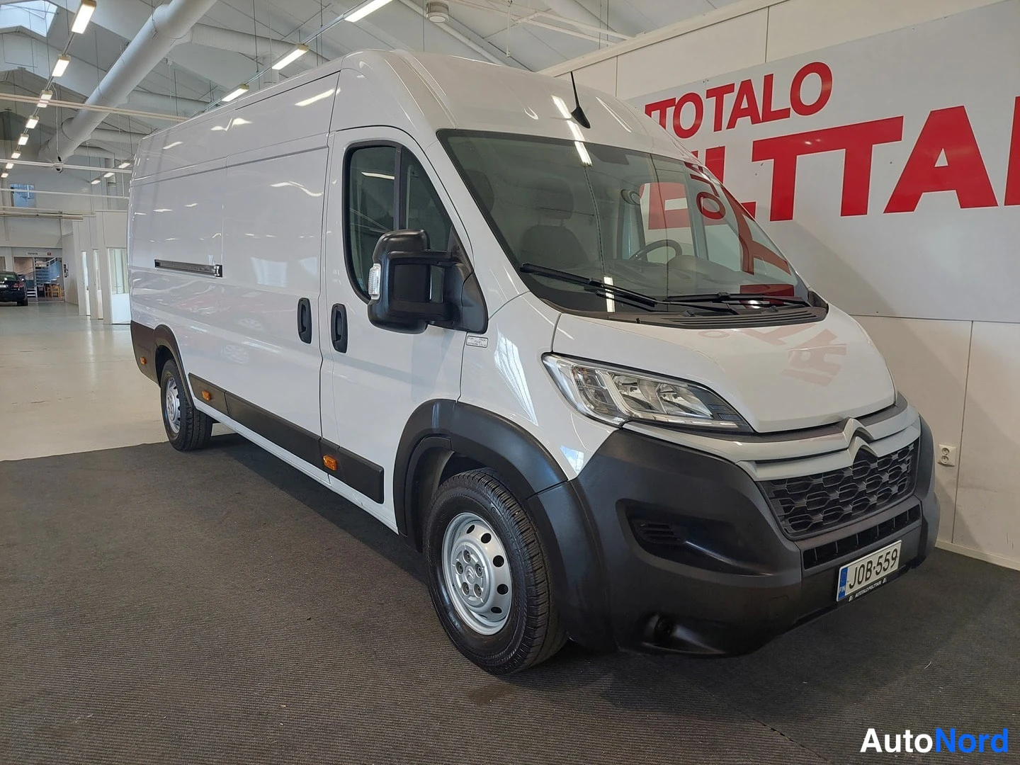 Etuviisto, nokka oikealle: Citroen Jumper -pakettiauto etuviistosta oikealta, valkoinen korimuoto ja tumma etupuskuri näkyvät sisätiloissa.