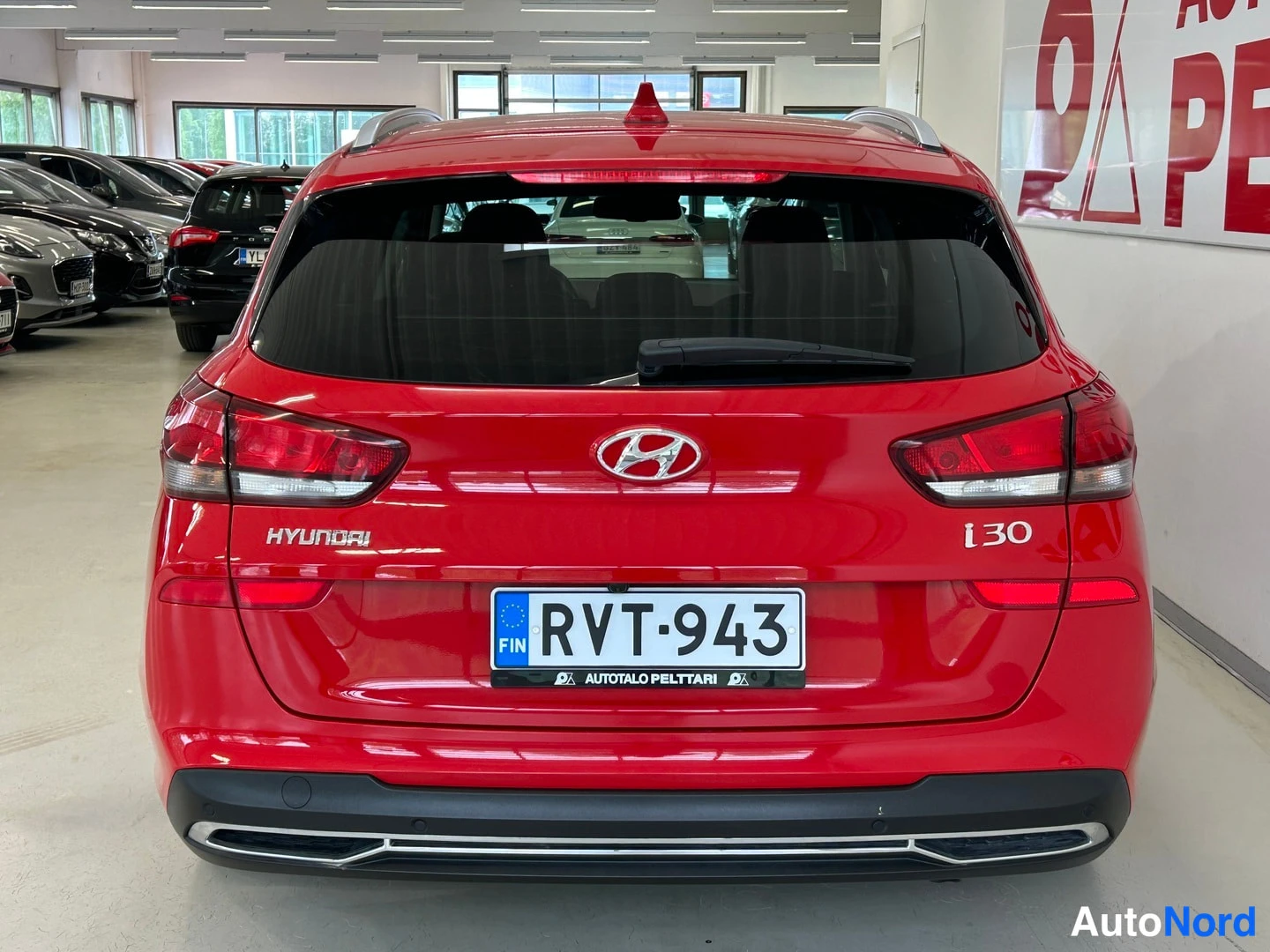 Takaa: Punaisen Hyundai i30:n takanäky; konepellissä HYUNDAI- ja i30-merkinnät, rekisteritunnus.
