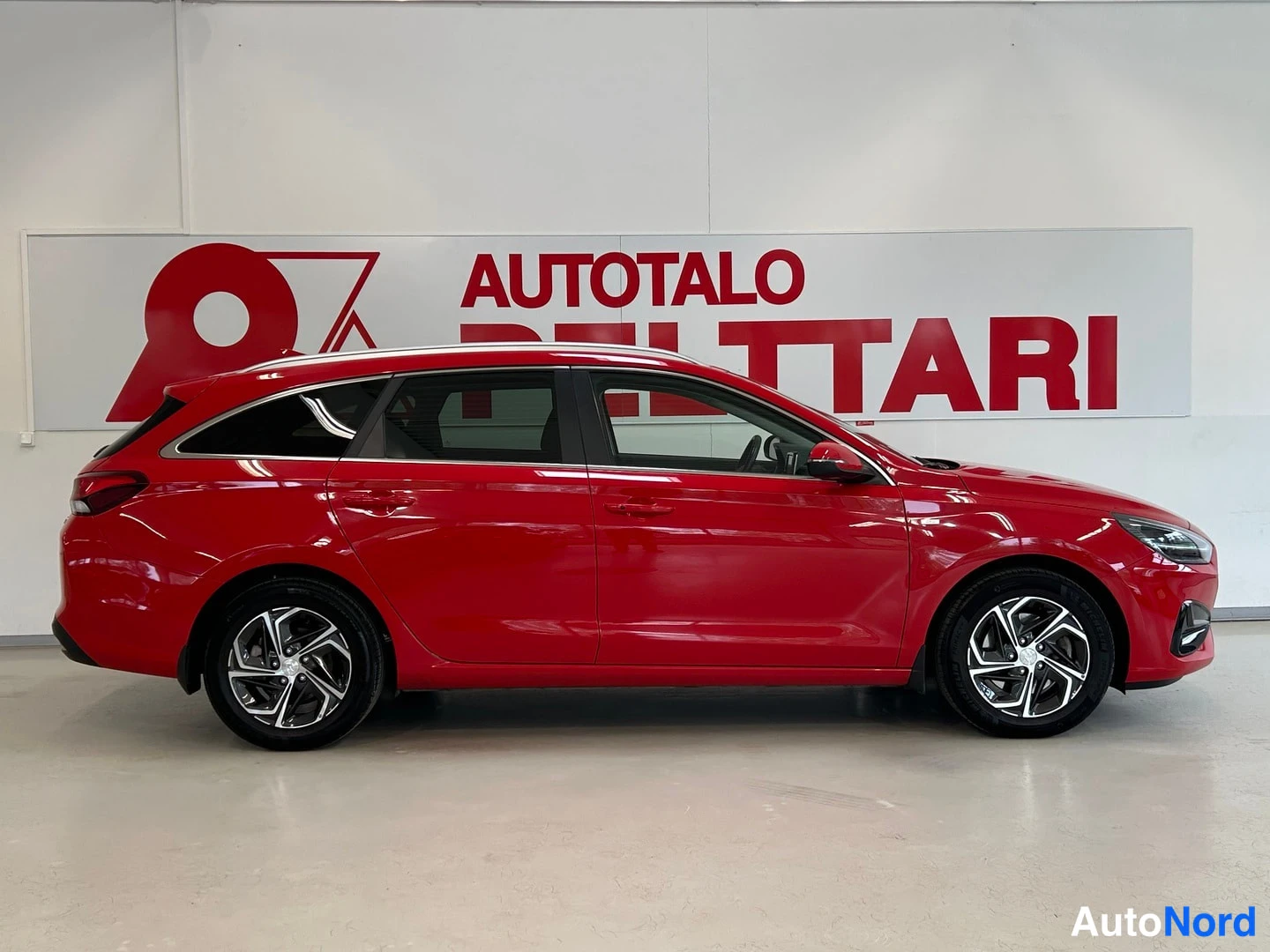 Sivulta: Punaisen Hyundai i30 Farmi -auton kylki sivusta sisätiloissa, korkeakattoinen farmarimalli.