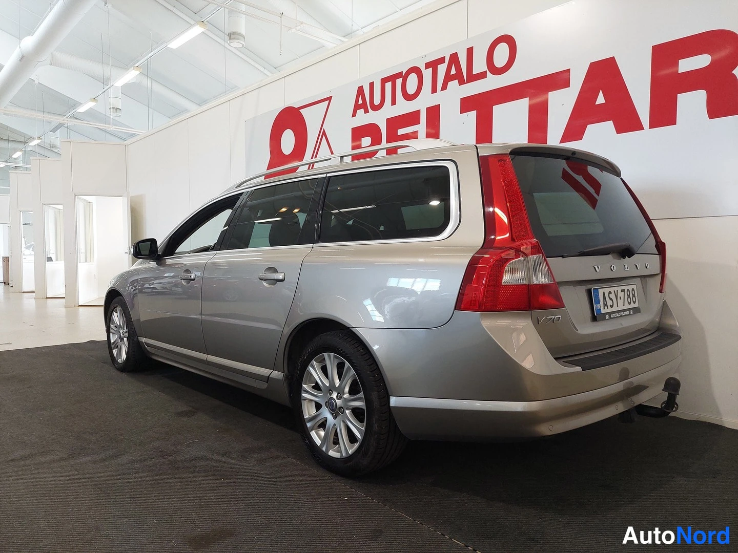 Takaviisto: Beige farmari takakulmasta vasemmalta: takavalot, peräluukki VOLVO-tekstillä, rekisteritunnus ja vetoaisa näkyvissä.