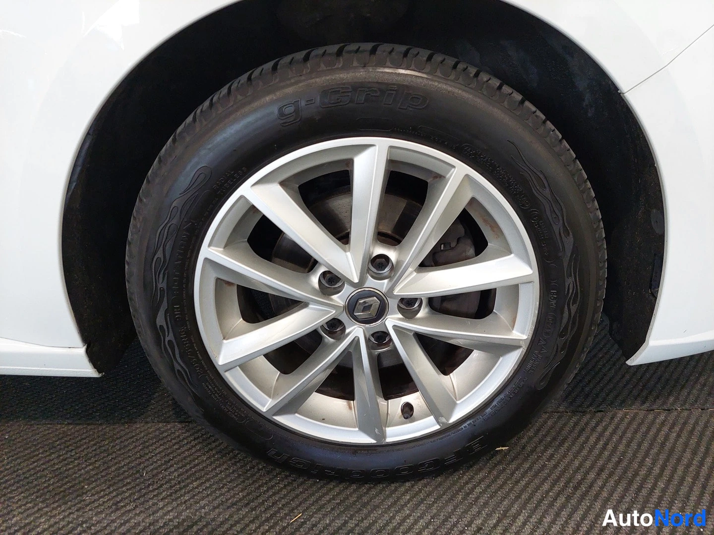 Yksityiskohta: Lähikuva auton etupyörästä, hopeiselta kehältä, jossa Renault-nappi, ja mustalta g-Grip-rengasta.