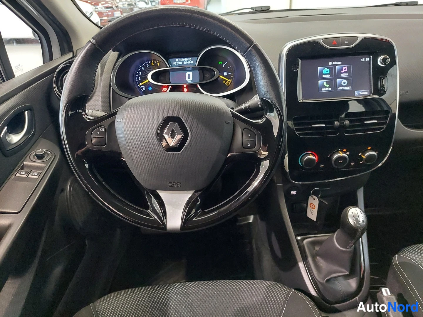 Muu: Ohjaamon lähikuva: Renault-ohjauspyörä, mittaristo, kosketusnäyttö ja manuaalivaihteiston vaihdevipu.