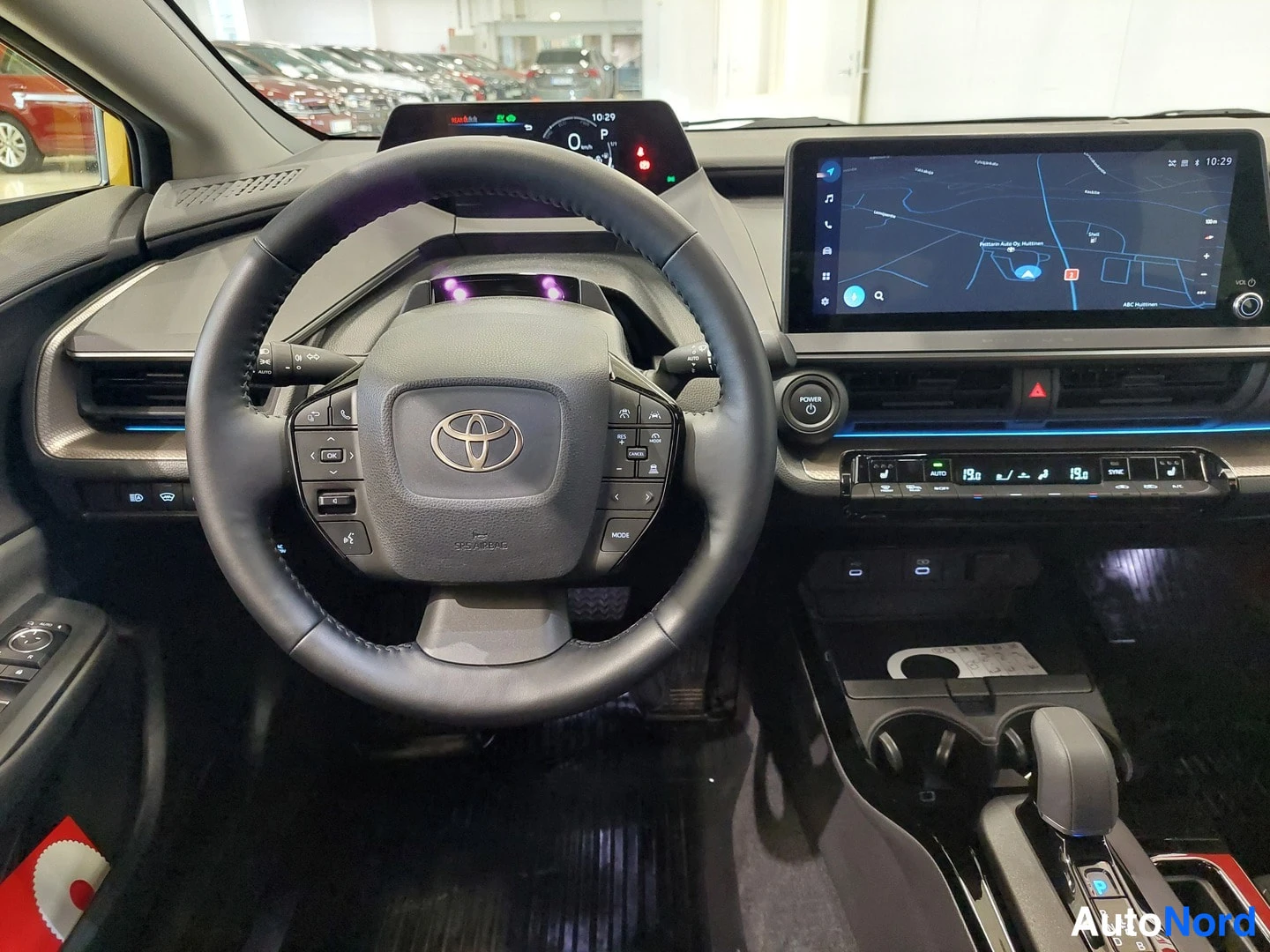 Muu: Ohjauspöydän lähikuva: Toyota-merkitty ohjauspyörä, digitaalinen mittaristo ja karttaa näyttävä keskinäyttö.