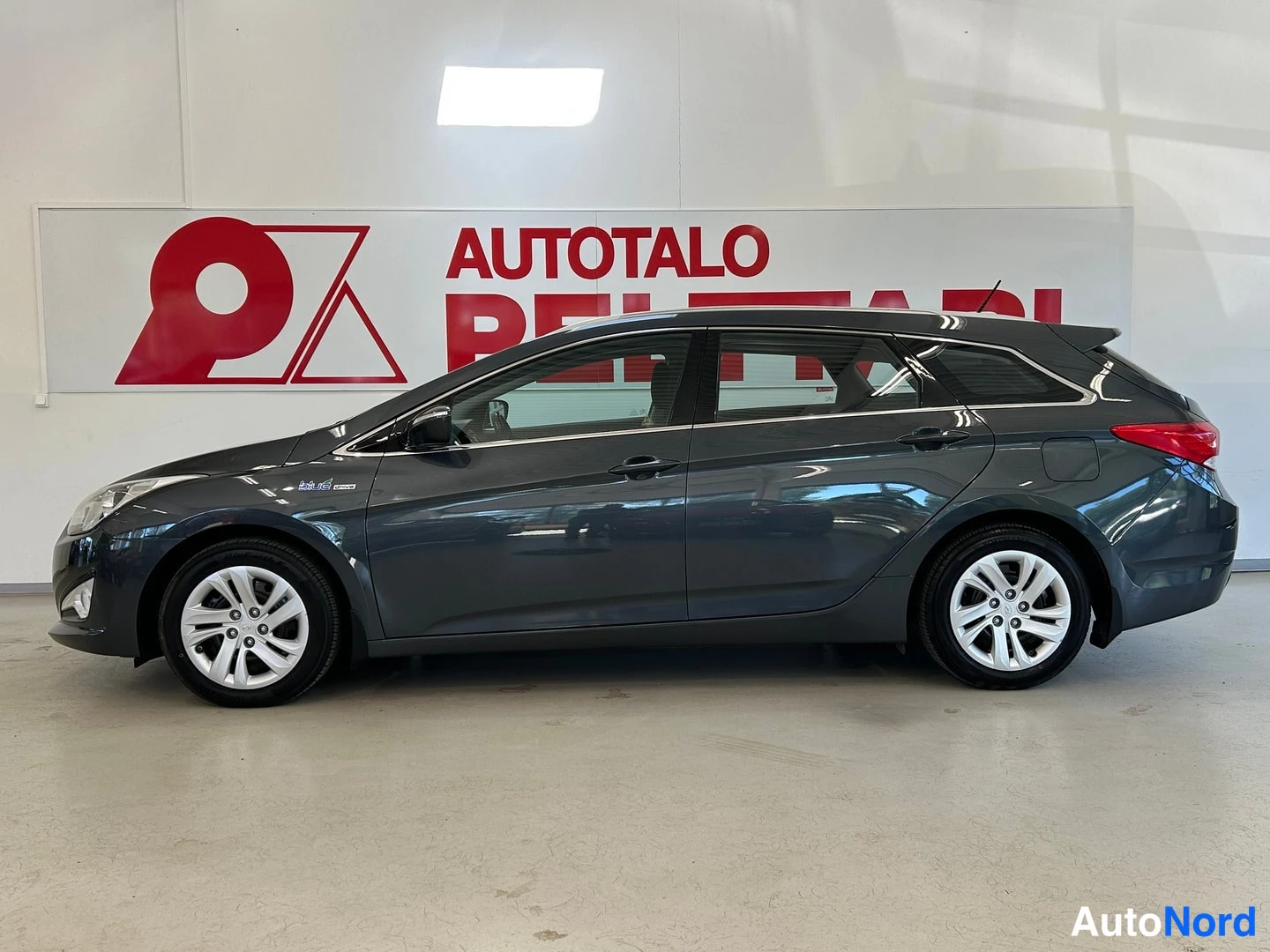 Etuviisto, nokka vasemmalle: Hyundai i40 -farmari auton sisätiloissa, tummanharmaa, sivulta etukolmasosa vasemmalta