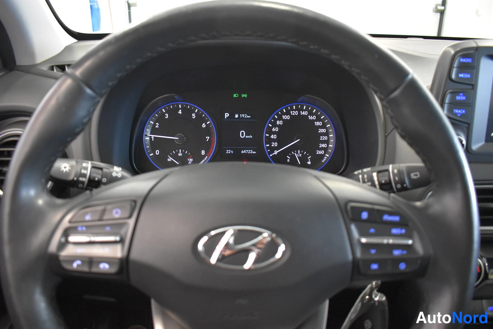 Muu: Hyundai-ohjauspyörä ja kojelaudan mittaristo lähikuvassa; näytössä P-vaihde, 0 km/h ja lukema 64732 km.