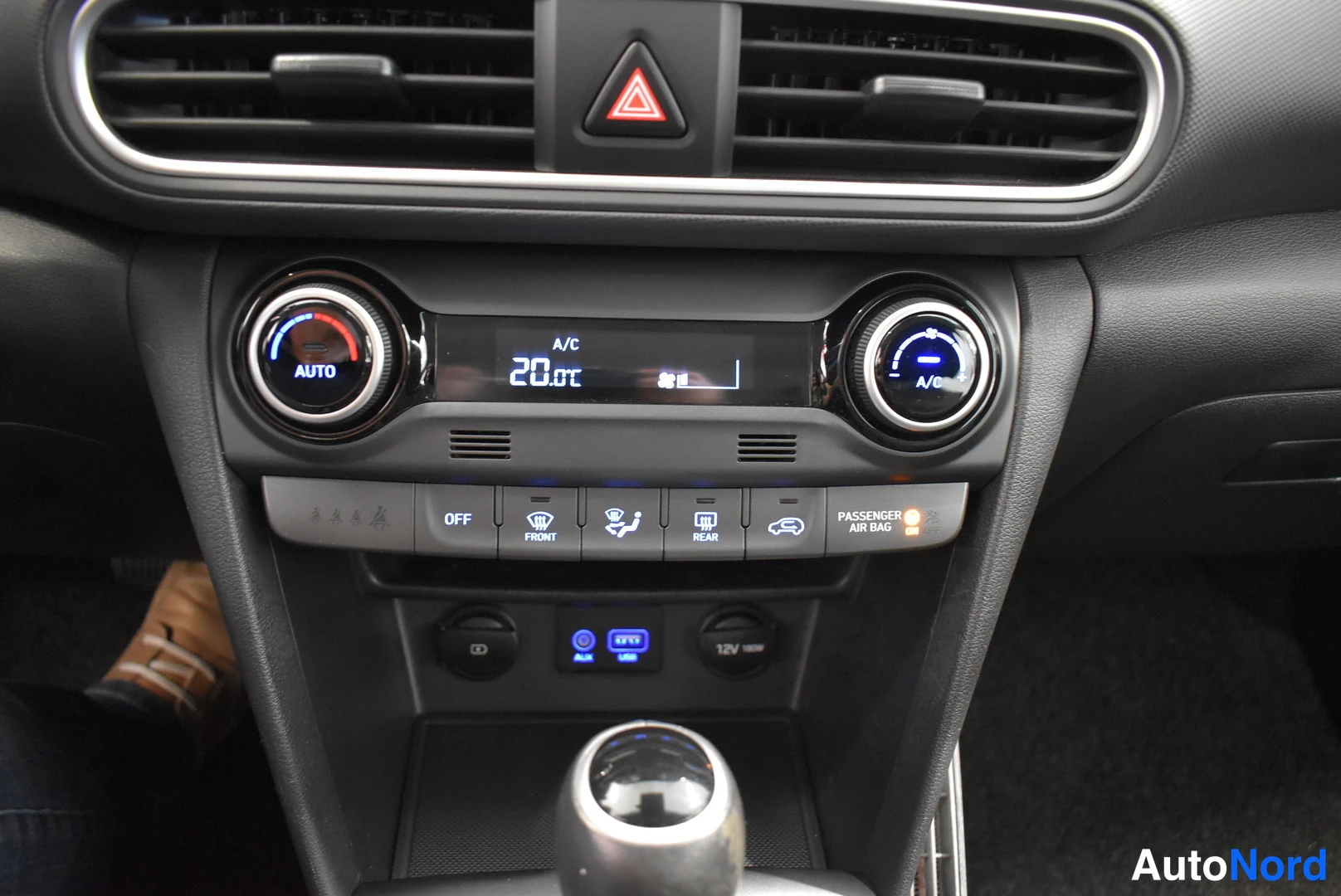 Muu: Keskikonsolin automaattinen ilmastointipaneeli, jossa näkyy A/C ja lämpötila 20.0°C, napit OFF, FRONT, REAR, PASSANGER AIR BAG, USB-portti, 12V-pistorasia ja va