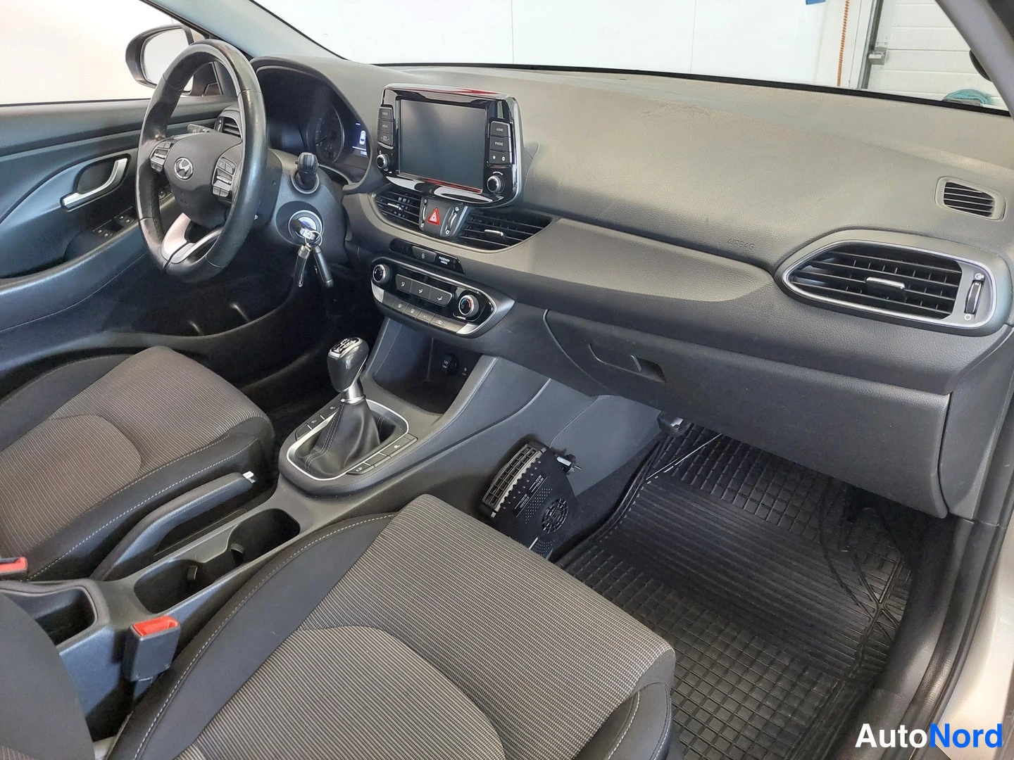 Muu: Hyundai i30 Farmrin etusivu: ohjaamo näkyy etupenkiltä kohti kojelautaa; halogeenimittaristo, kosketusnäytöllinen infotainment-laite, manuaalivaihteen valitsin,