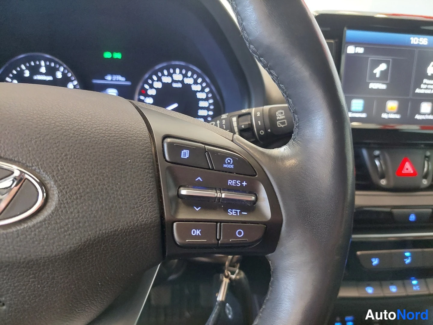 Muu: Lähikuva Hyundai i30 Farmrin rattiin integroiduista napeista: näkyvät nappimet RES+, SET−, MODE ja OK, taustalla mittaristo ja kosketusnäyttö.