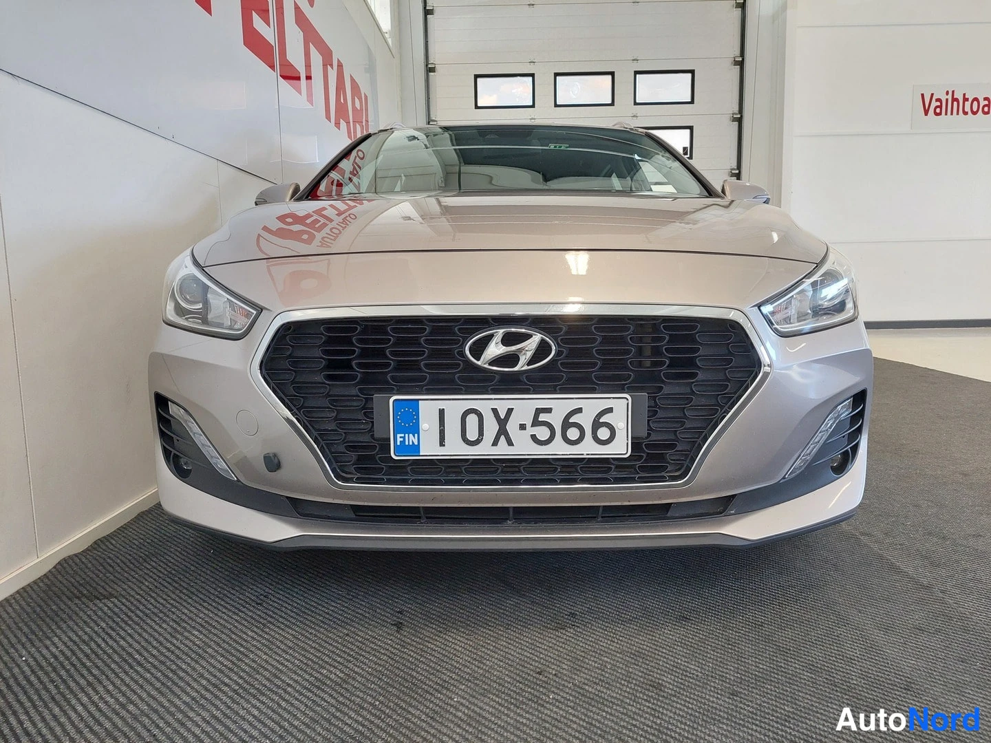 Edestä: Hyundai-henkisen farmariauton etunäkymä eteinen konepellillä ja grillaatilla, rekisterikilpi 10X-566.