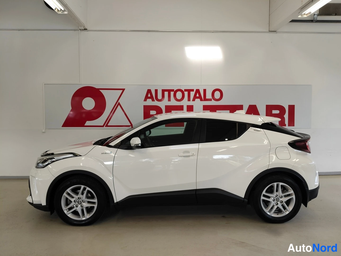 Sivulta: Valkoinen Toyota C-HR sivulta Autotalo Pelttari -logon edessä