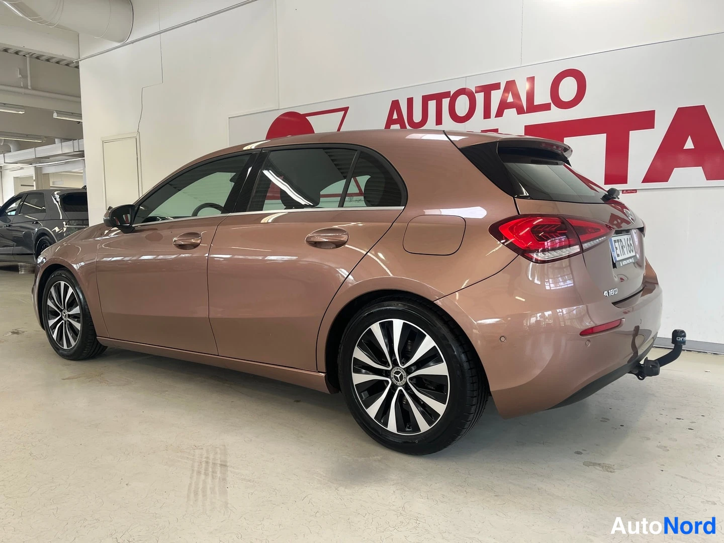Takaviisto: Mercedes-Benz A-sarjan viistosti takaa vasemmalta kuvattu hatchback-autotallissa; korin väri kupariruskea.