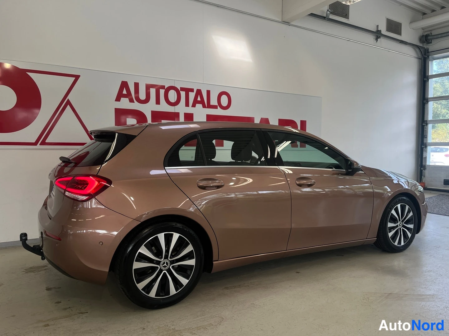 Takaviisto: Mercedes-Benz A-sarjan viistosti takaa oikealta kuvattu hatchback-autotallissa; korin väri kupariruskea.