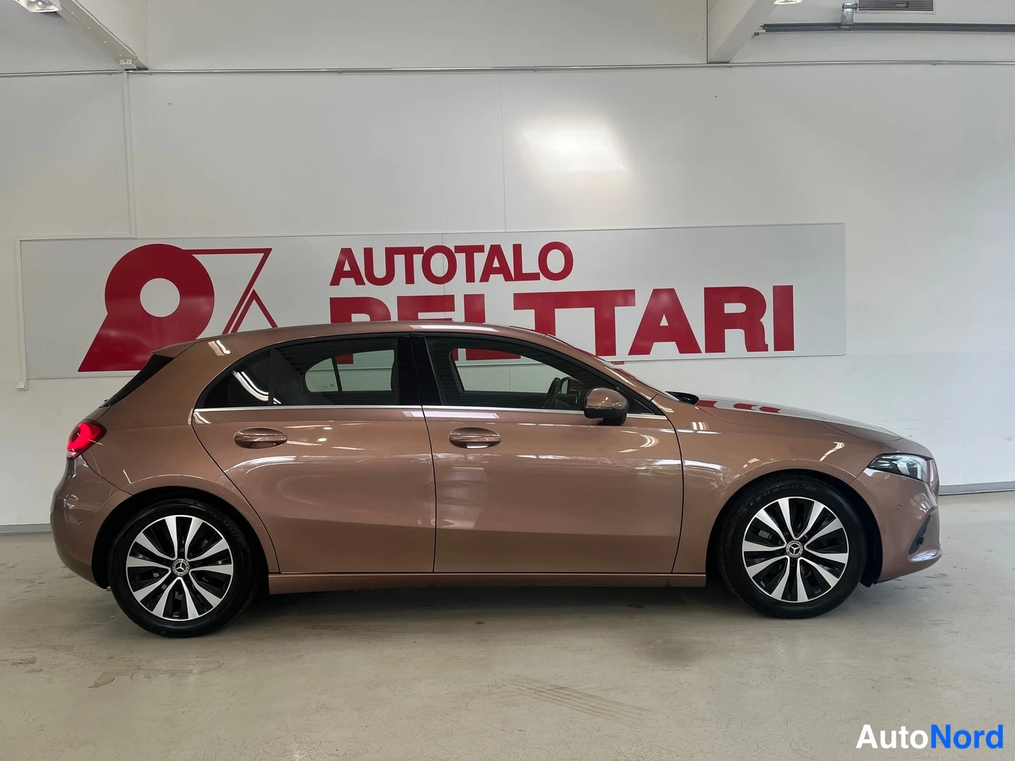 Sivulta: Mercedes-Benz A-sarjan vasemmalta sivulta kuvattu hatchback-autotallissa; korin väri kupariruskea.