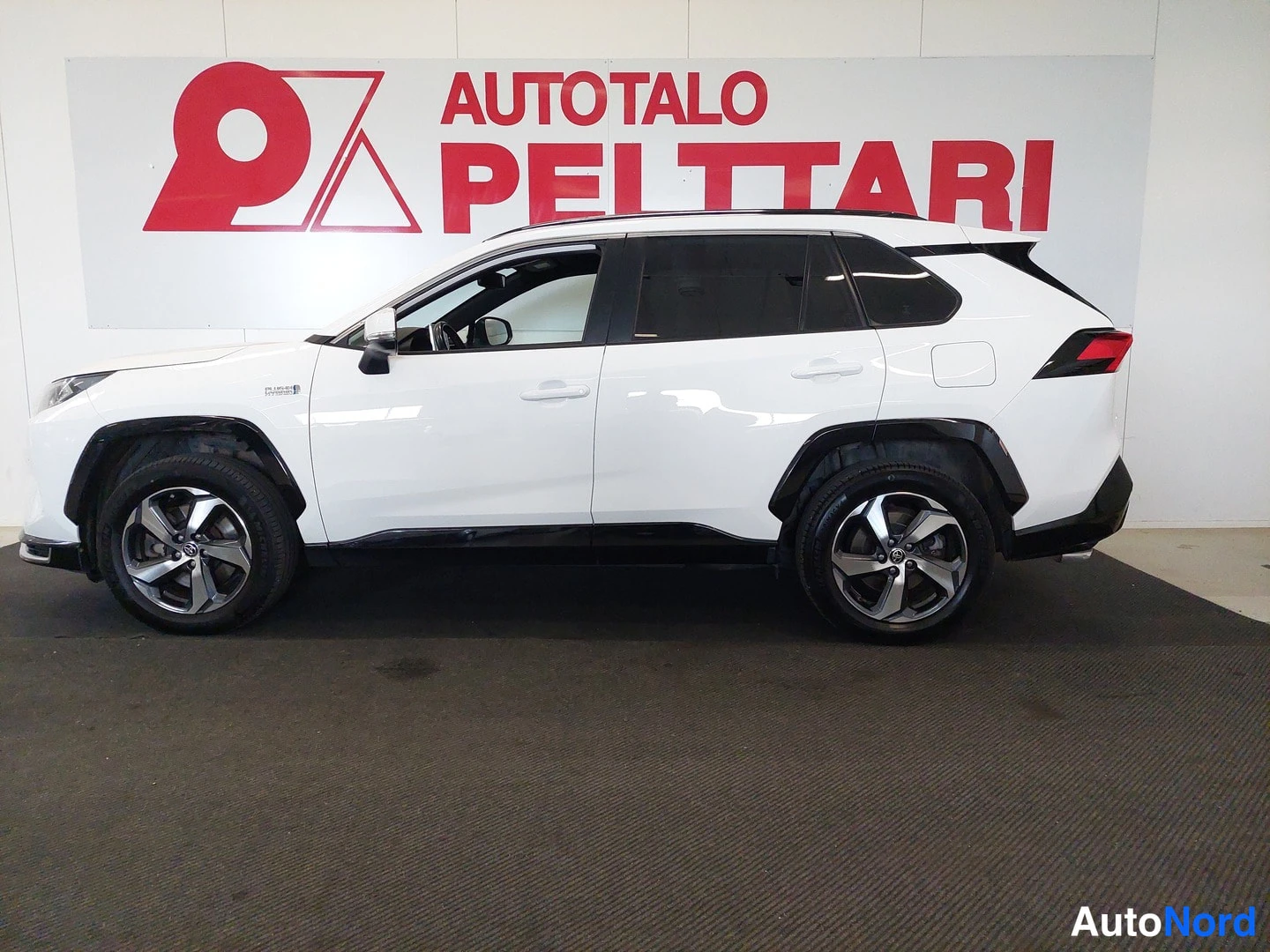 Sivulta: Valkoinen Toyota RAV4 sivusta sisätiloissa.