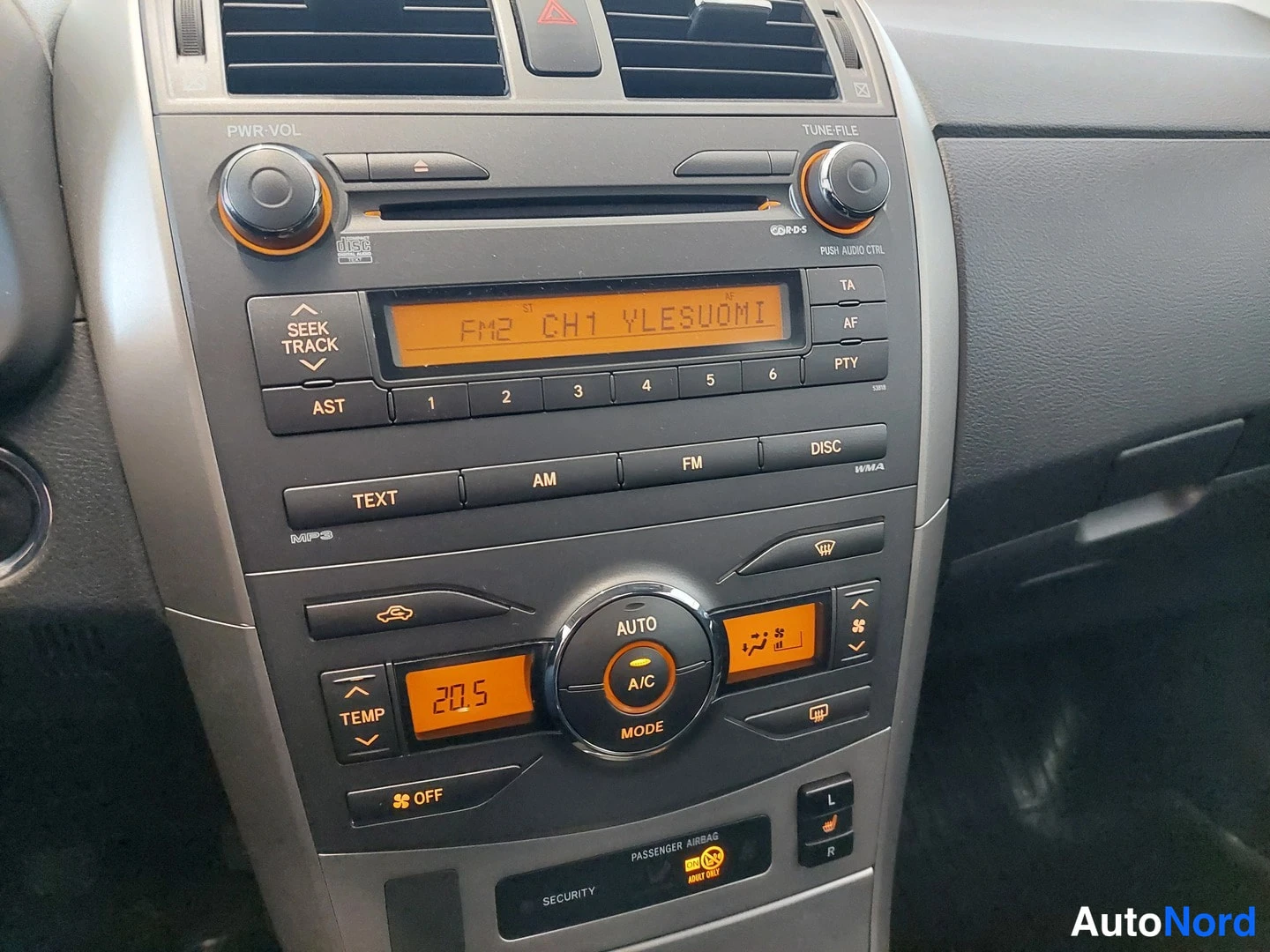 Yksityiskohta: Kojeiston keskusyksikkö: radio CD-soittimella ja automaattinen ilmastointi, näytössä teksti FM2 CH1 YLESUOMI.