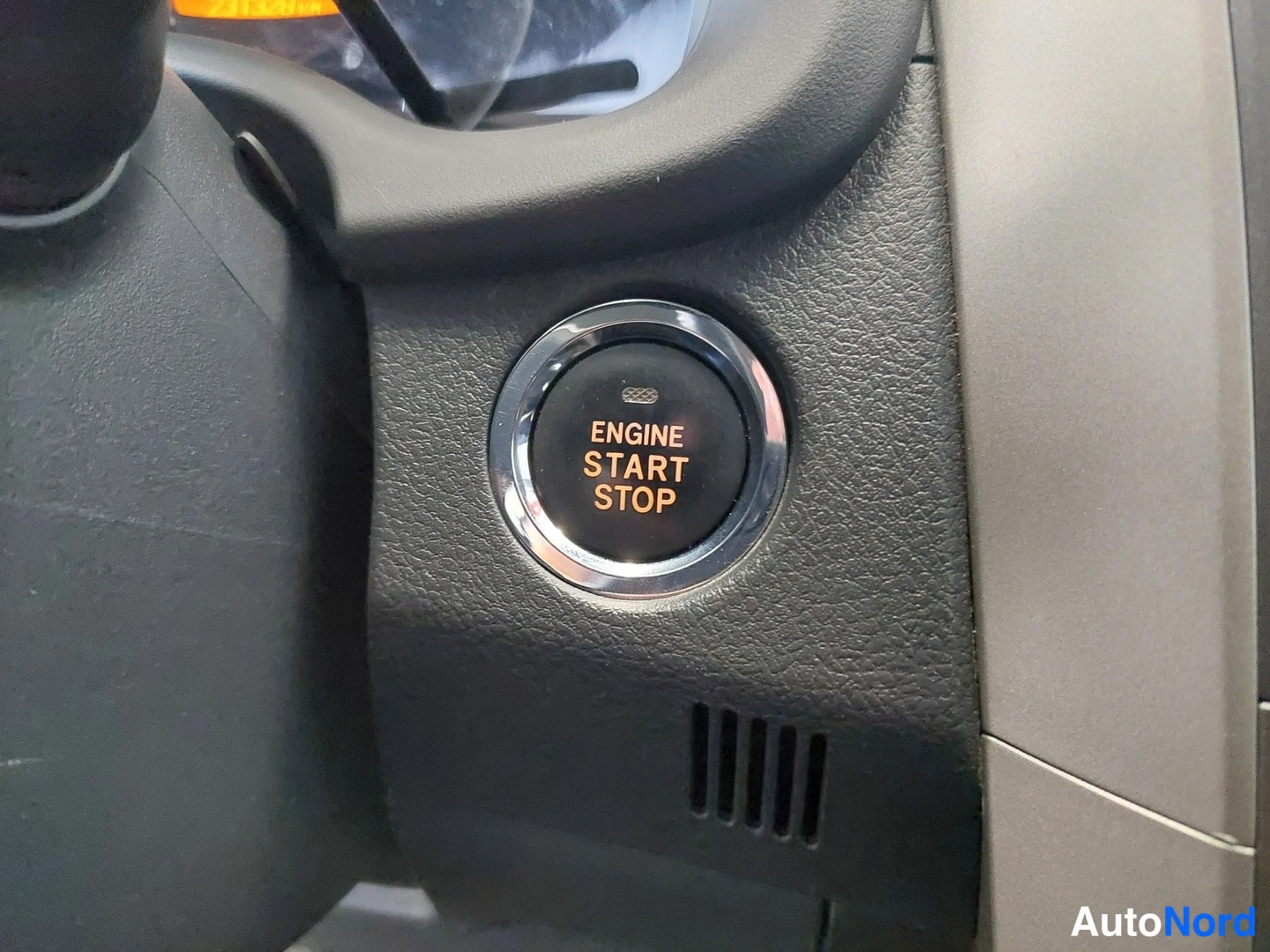 Yksityiskohta: Start-painike: pyöreä ENGINE START STOP -painike mittariston yhteydessä.