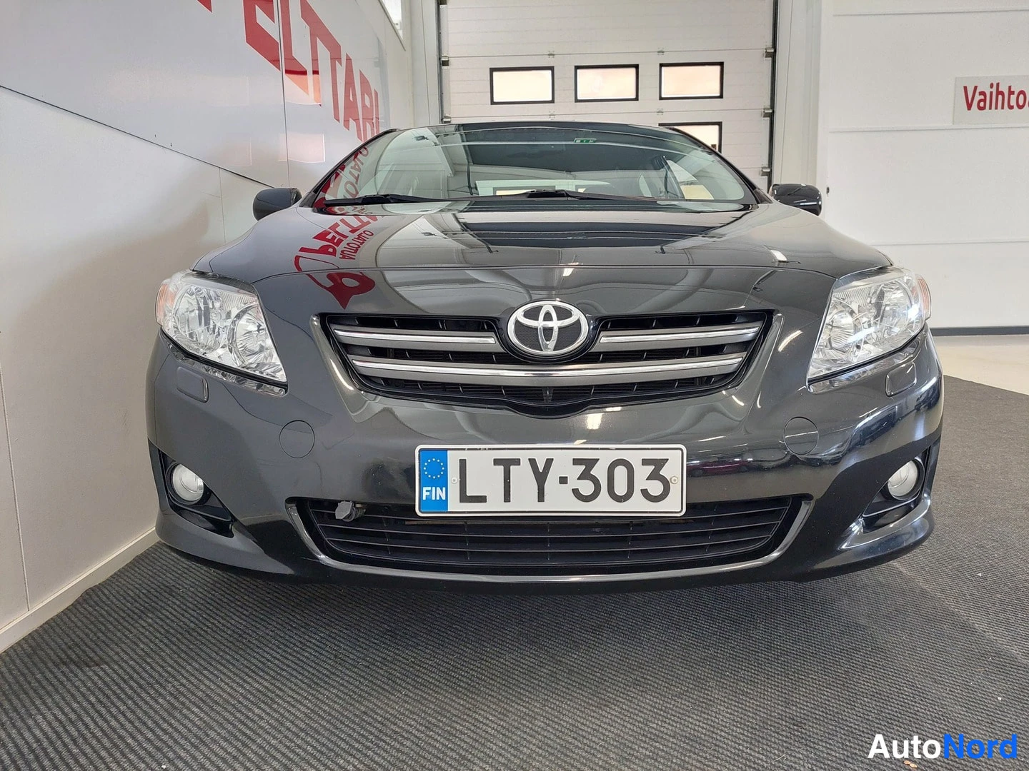 Edestä: Auton etupää suoraan edestä: harmaakorinen Toyota, rekisteritunnus.