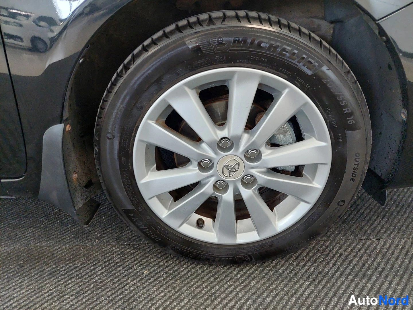 Yksityiskohta: Auton vanteen ja Michelin-renkaan lähikuva, vanteessa Toyota-merkki