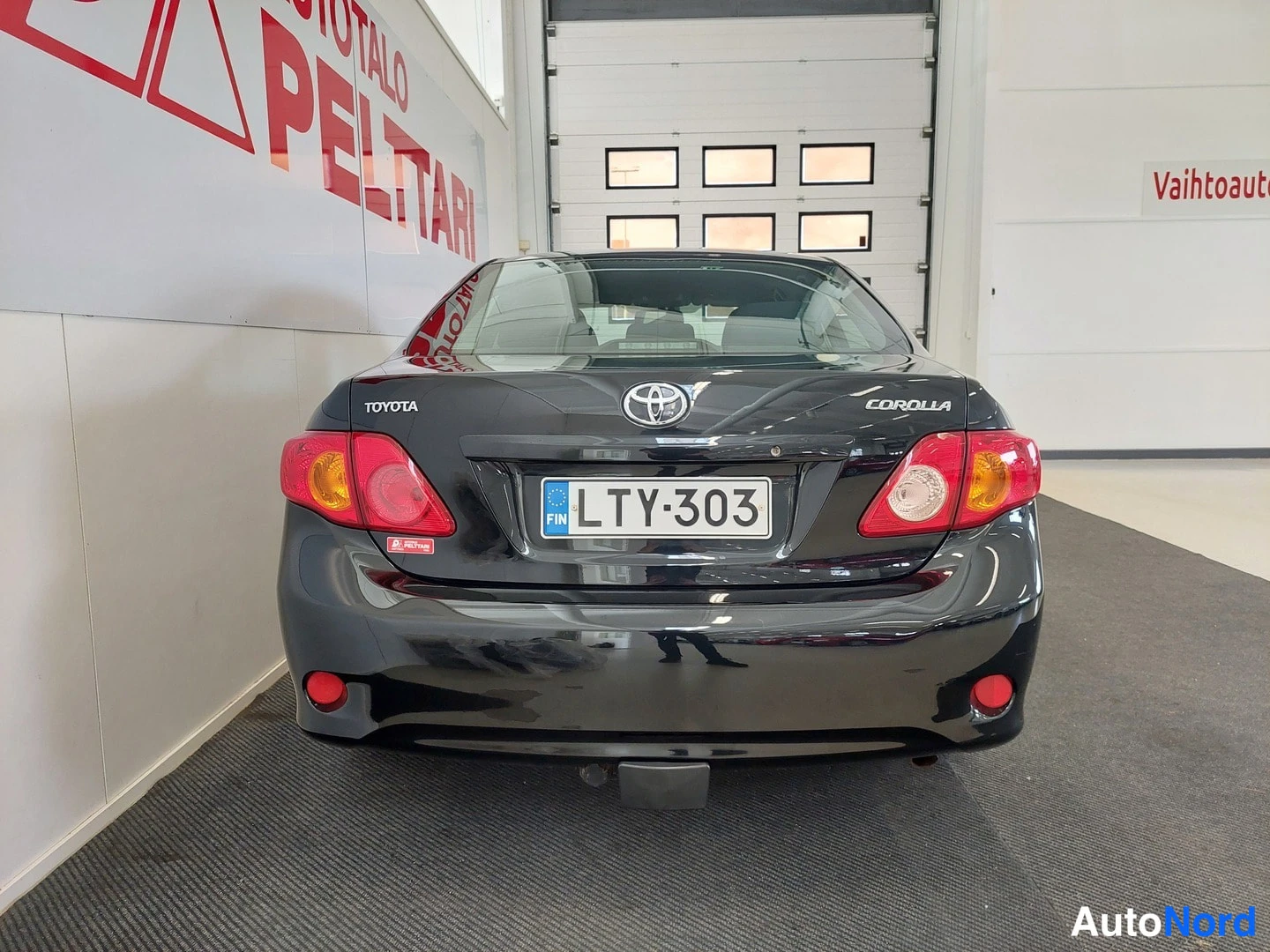 Takaa: Mustan sedanin takaosa: Toyota- ja Corolla-merkinnät sekä rekisterikilpi.