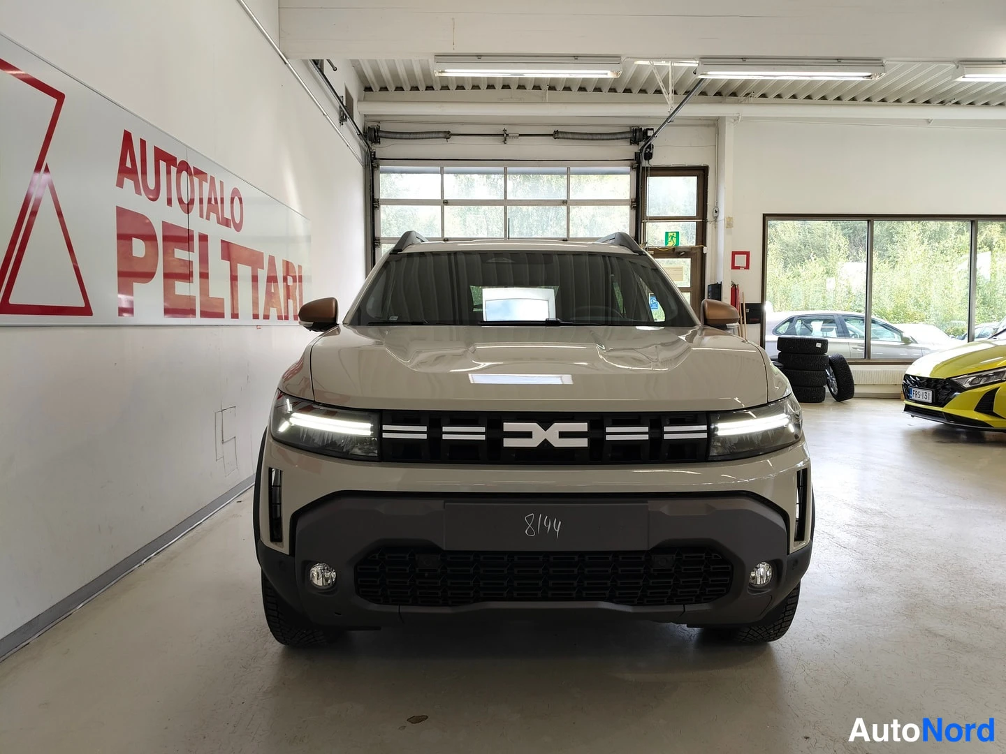 Edestä: Auto suoraan edestä kuvattuna; beige koriväri, tumma etupanssari ja LED-päivaloimu.
