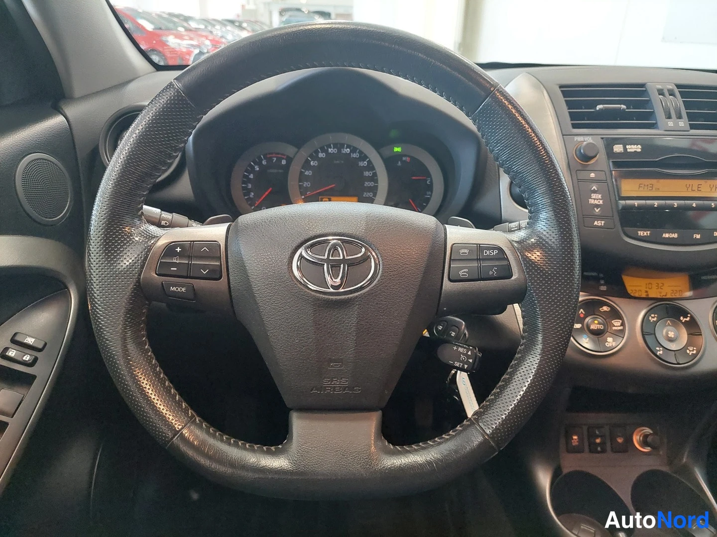 Muu: Ohjauspyörä ja kojelauta sisältä; Toyota-merkki, mittaristo ja radio näkyvät.