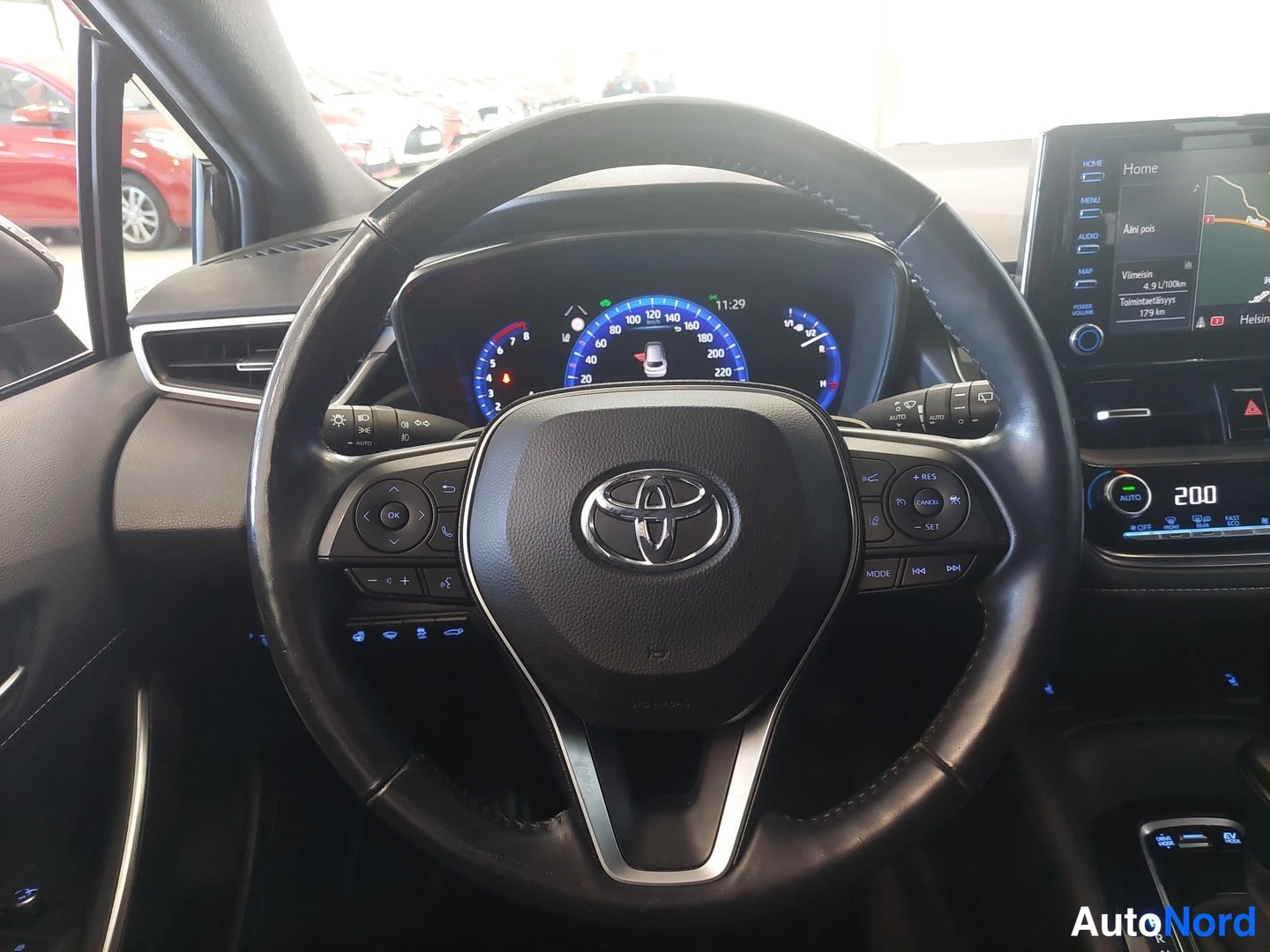 Takaa: Toyota-ohjauspyörä lähikuvassa, digitaalinen mittaristo näkyvissä ja osa infotainment-näytöstä.
