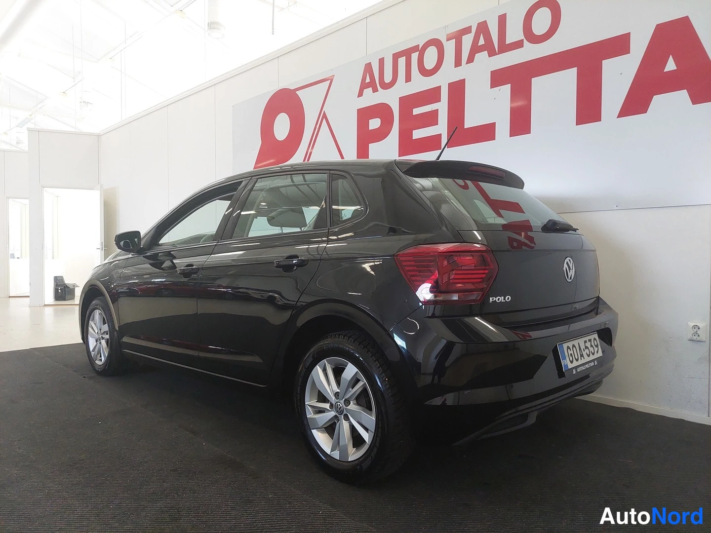Takaviisto: Mustan Volkswagen Polon takaosa vasemmalta takaviistöstä showroomissa.