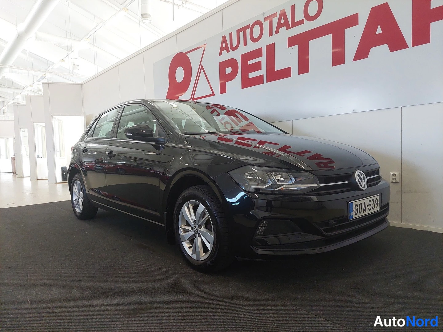 Etuviisto, nokka oikealle: Musta Volkswagen Polo etuviistosta oikealta, rekisteritunnus, hopeavanteet.