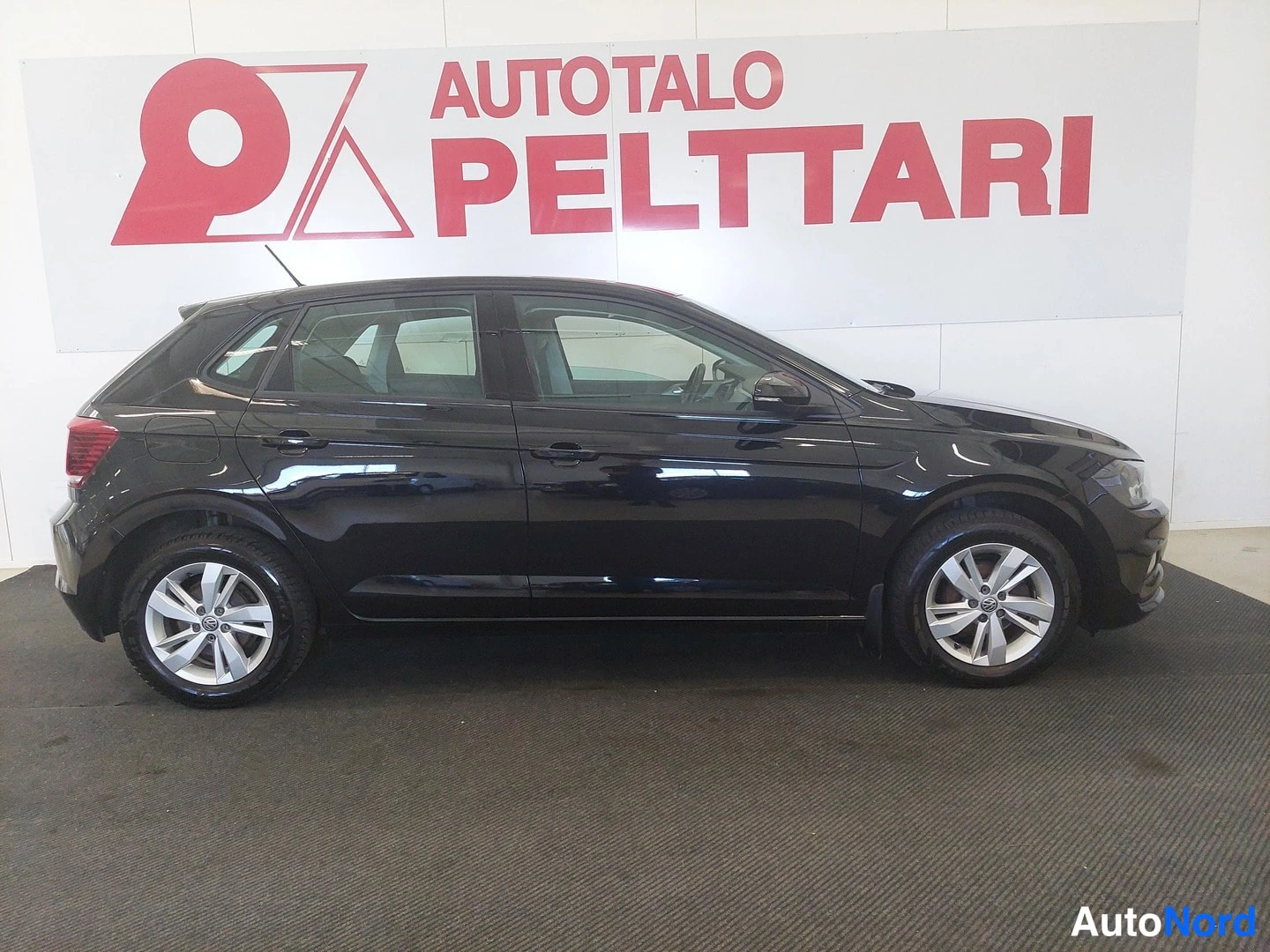 Takaviisto: Musta Volkswagen Polo sivusta taka­kulmasta, perä vasemmalla, hopeavanteet.