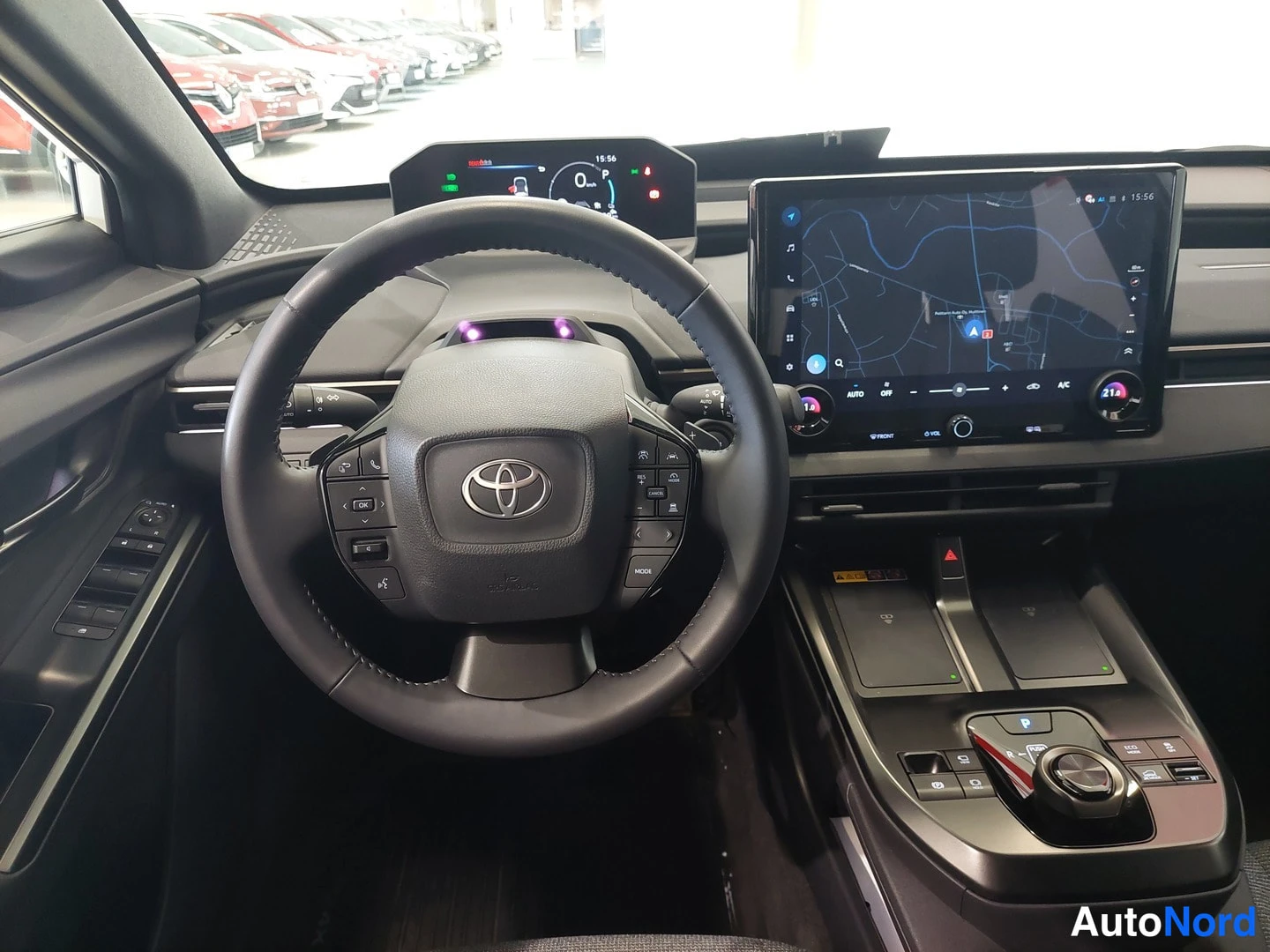 Muu: Ohjaamojen kuva ohjauspyörästä ja keskinäytöstä, Toyota-merkki näkyvissä ja infotainment-järjestelmä päällä.